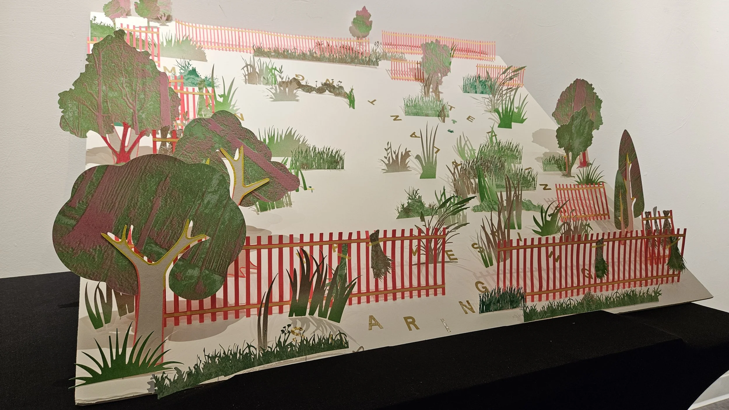 A detailed paper diorama of a garden scene with trees, shrubs, grass, fencing, and small animals, incorporating multiple layers and colors.