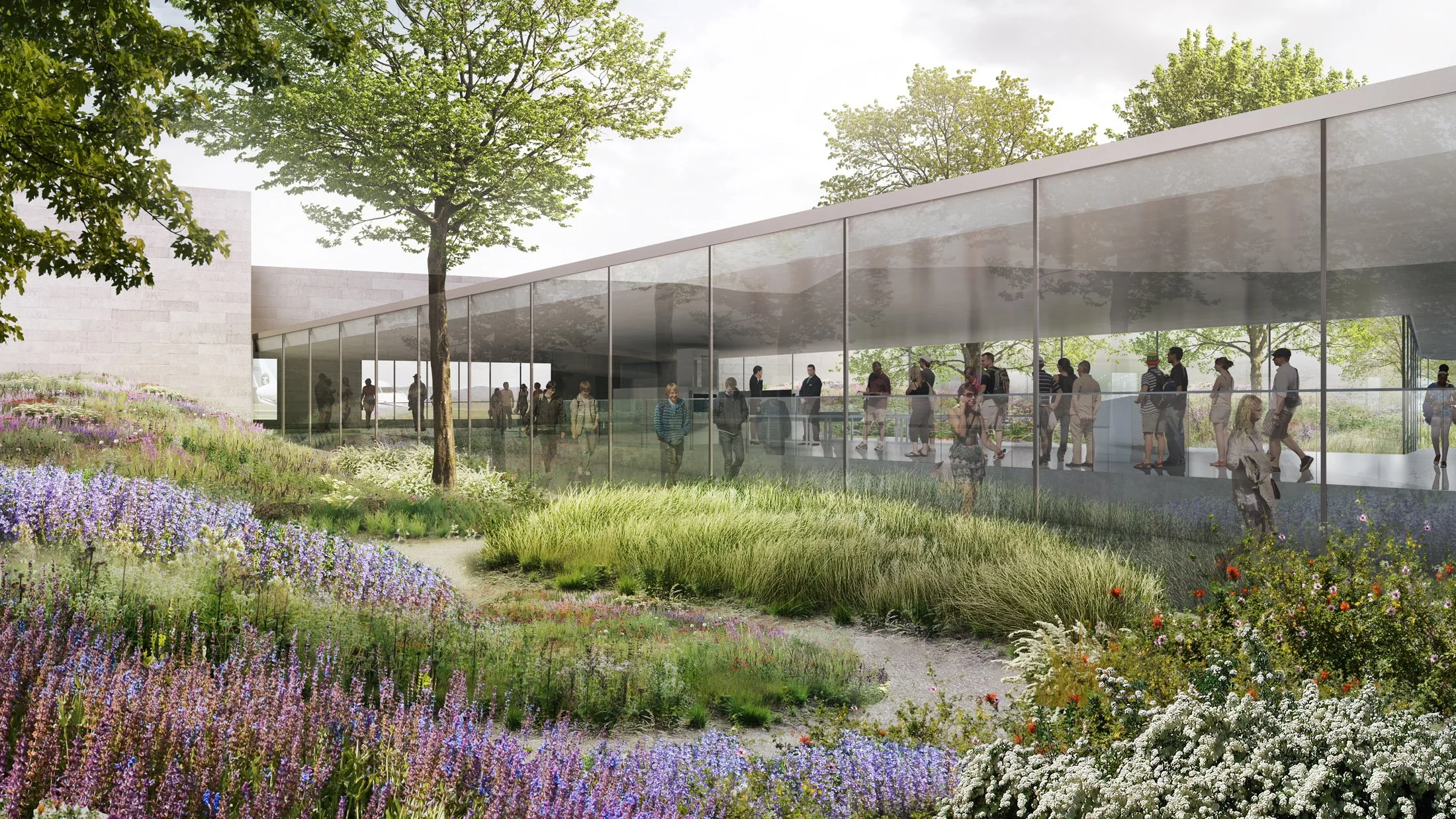 A modern glass building with people inside and outside, surrounded by lush greenery and colorful flowering plants.