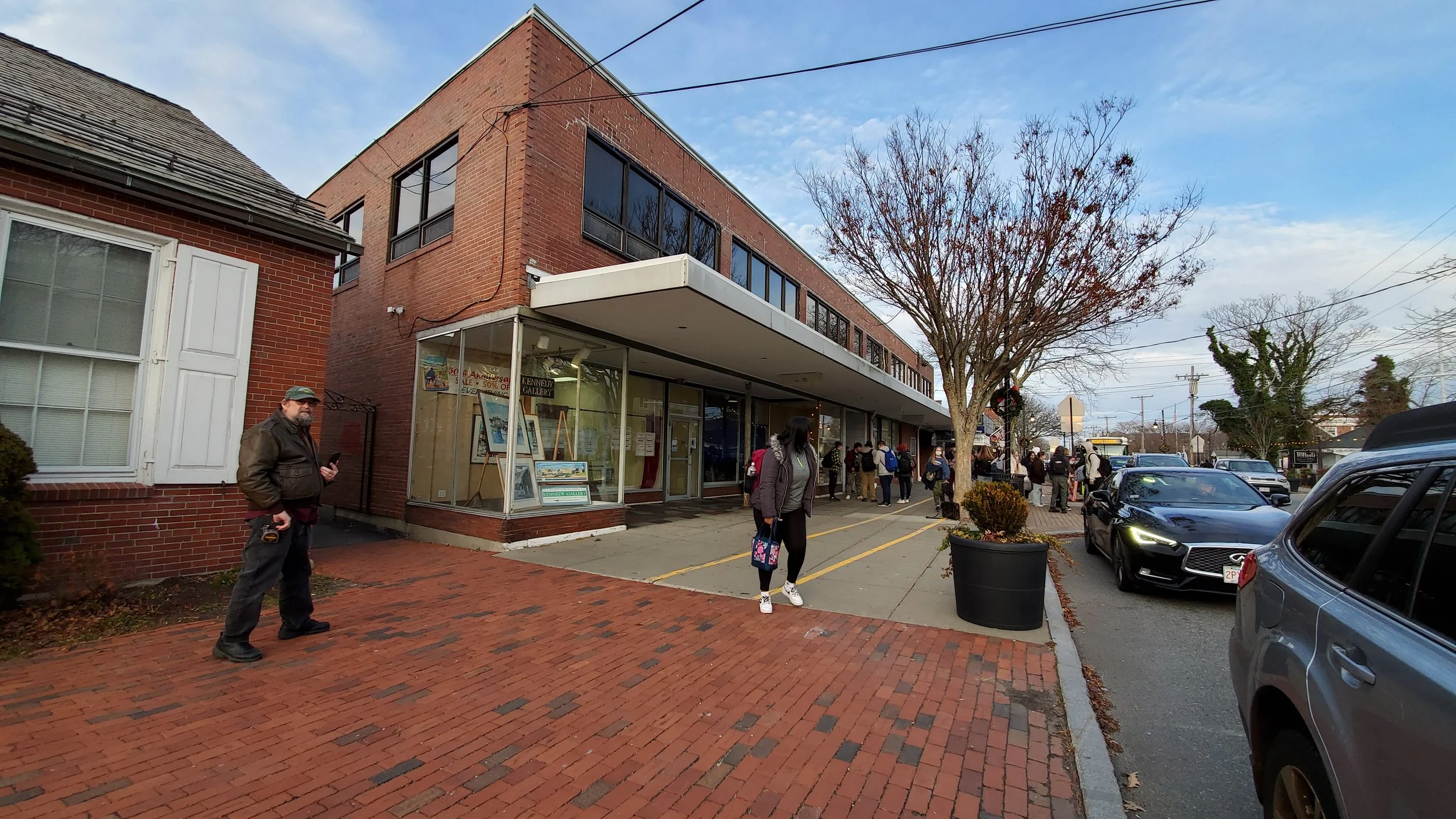 Exterior view of brick museum that has large windows displaying space and air pieces, a tree with few leaves.