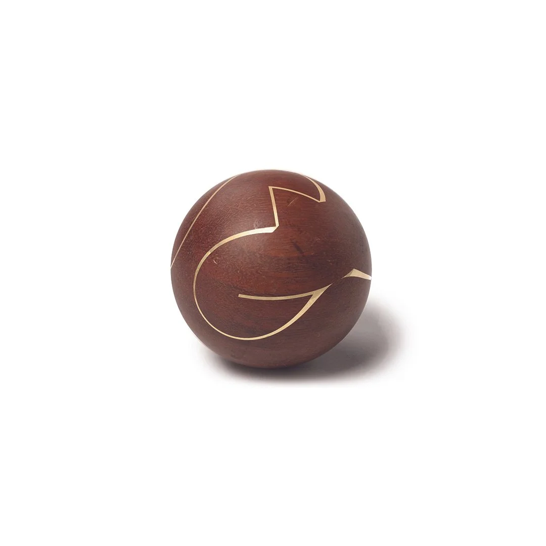 A wooden sphere with a carved gold lightning bolt design on a white background.