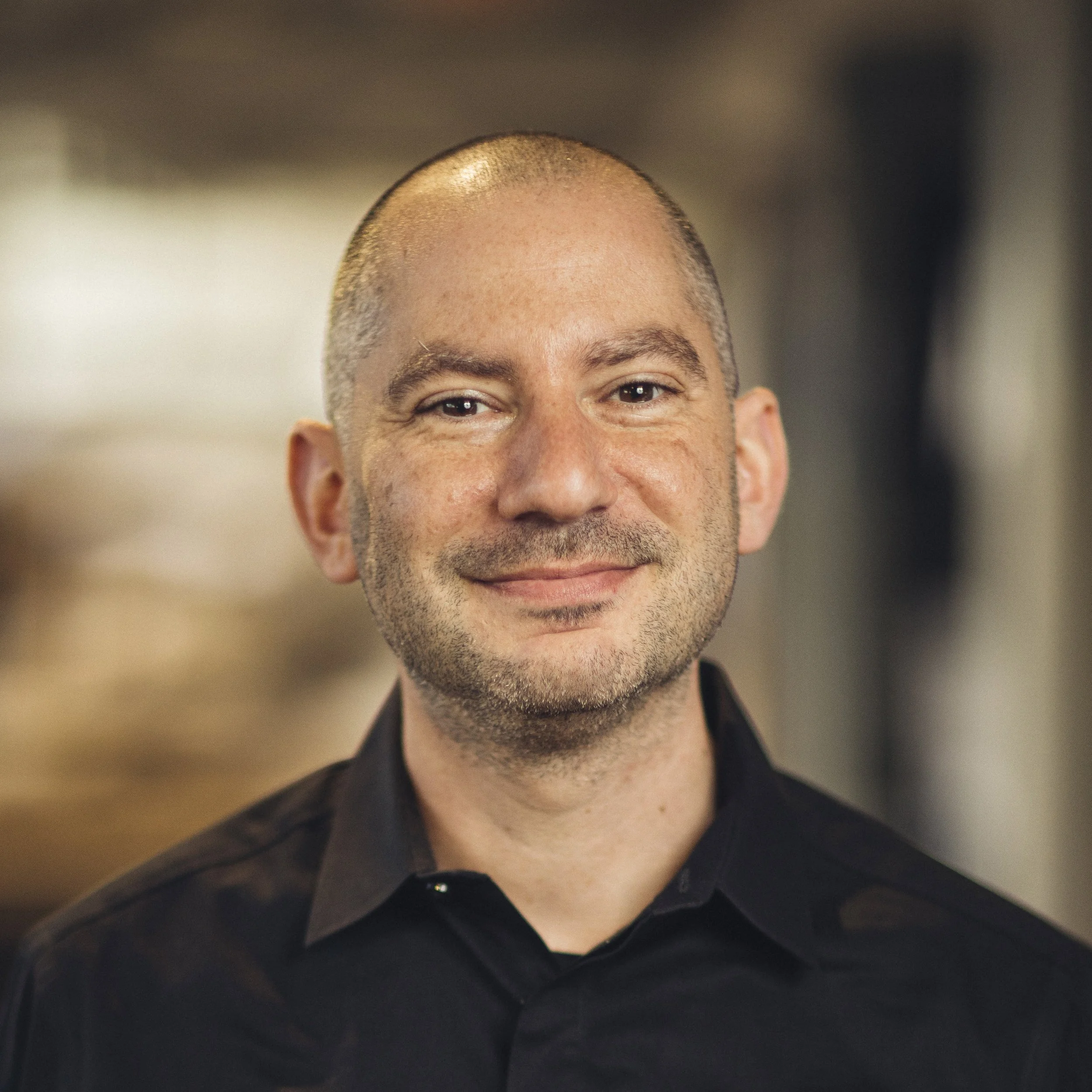 Close-up of a smiling man wearing a black shirt.