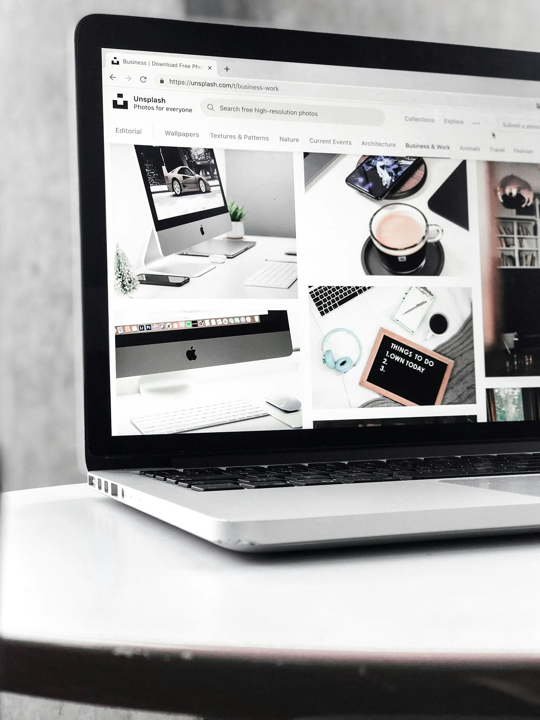 A laptop displaying a collage of photos of desk setups, including Apple iMacs, a coffee mug, headphones, and stationery.