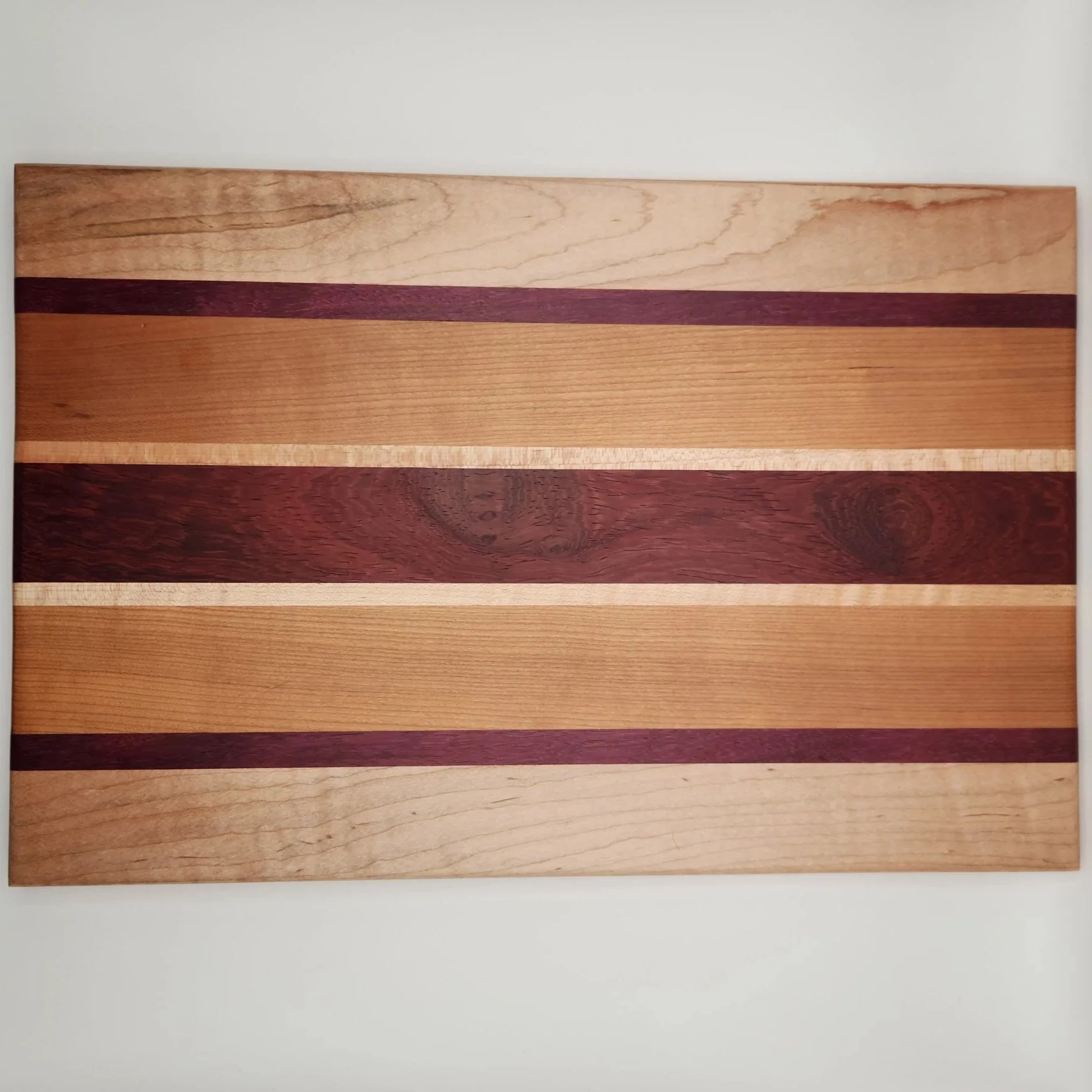 Close-up view of a wooden panel made from multiple strips of different types of wood with varying natural colors and grain patterns.