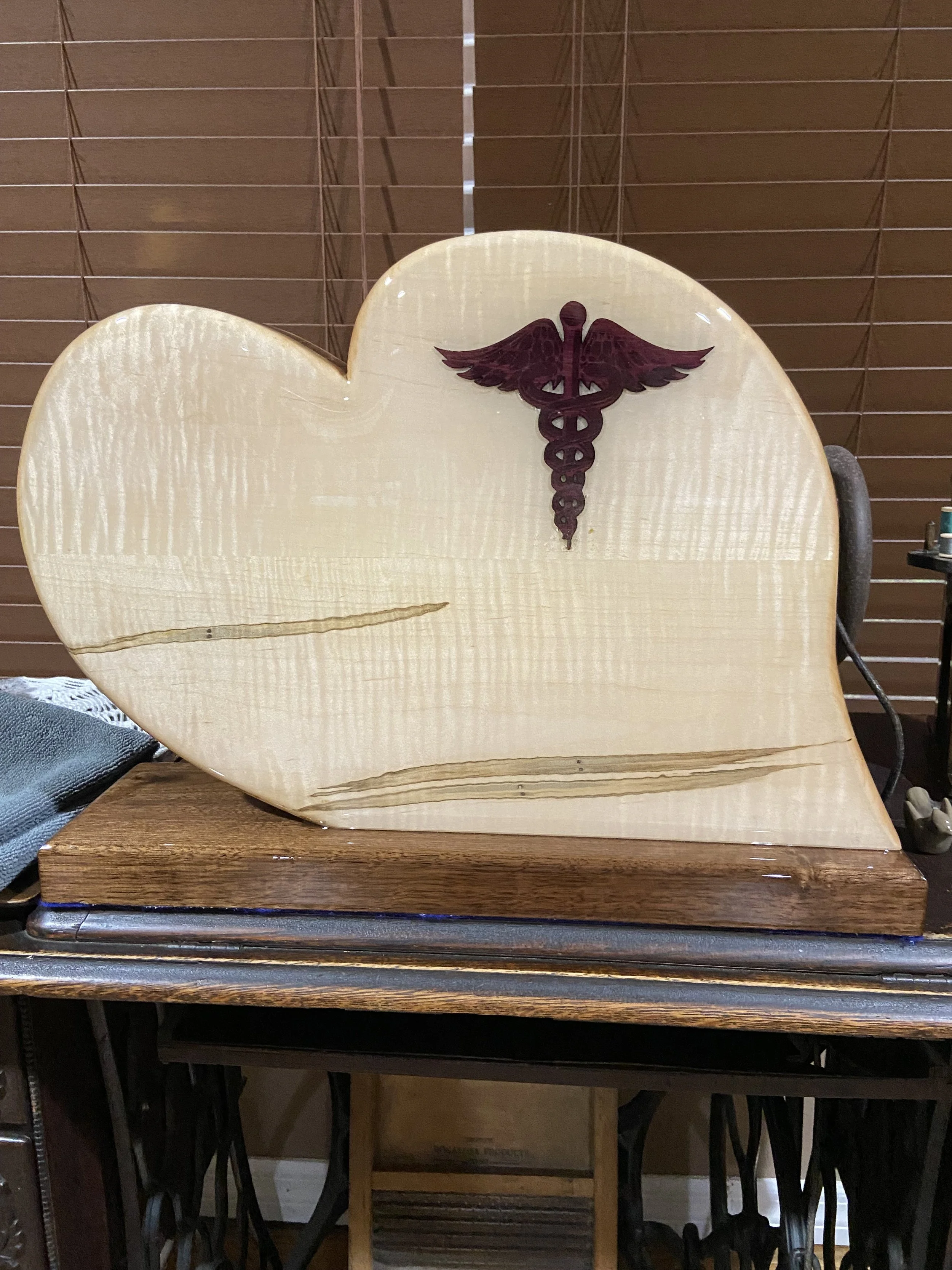 Custom wood heart shaped urn featuring a caduceus symbol with wings and a staff