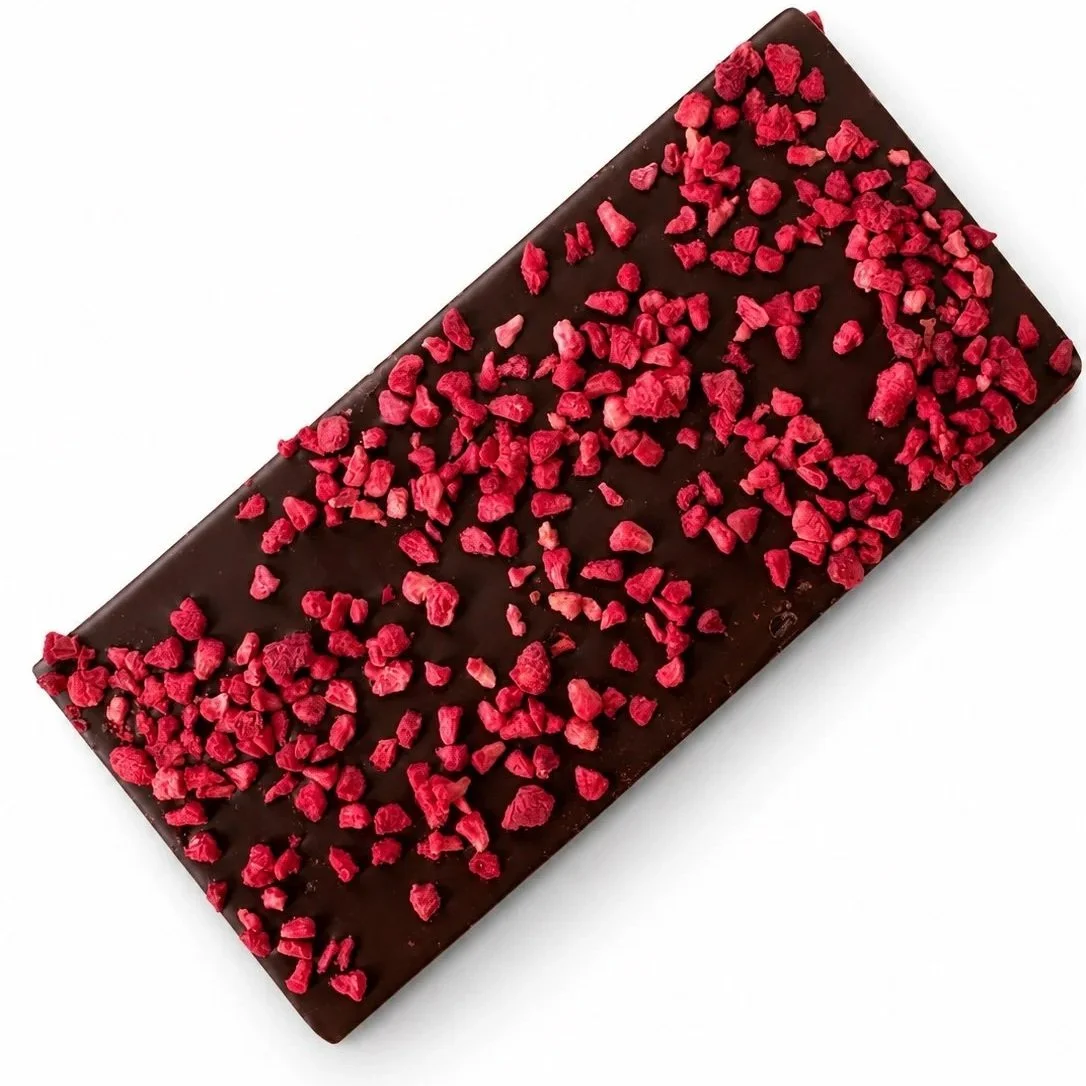 Dark chocolate rectangular bar covered with bright red freeze-dried raspberry pieces.