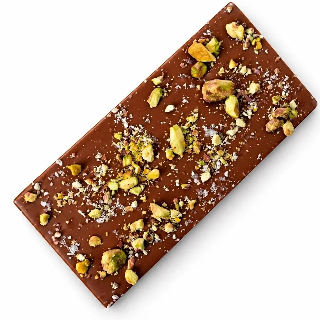 milk chocolate rectangular bar covered with crushed green pistachios and sea salt flakes