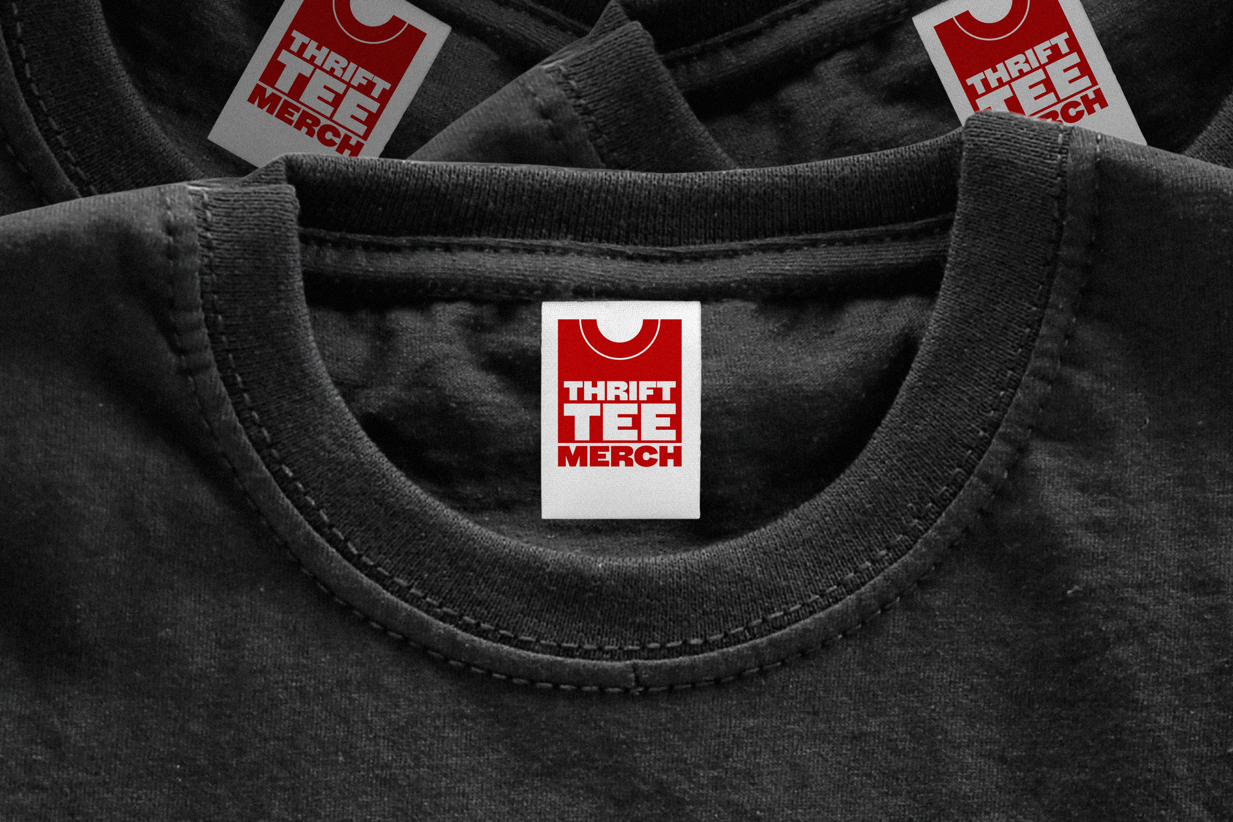 Black T-shirt with three red-and-white “Thrift Tee Merch” tags