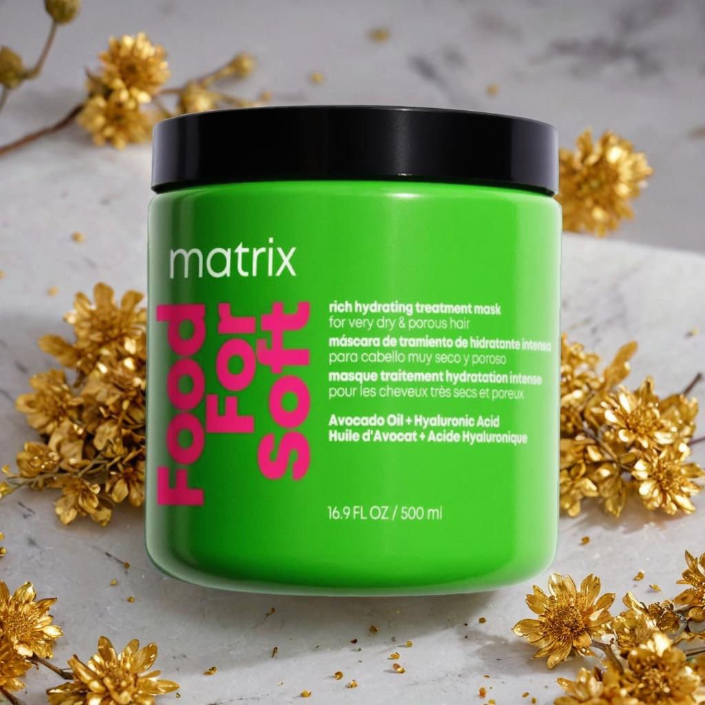 Green container of Matrix Face Food Soft mask with black lid, surrounded by dried golden flowers on a light marble surface.
