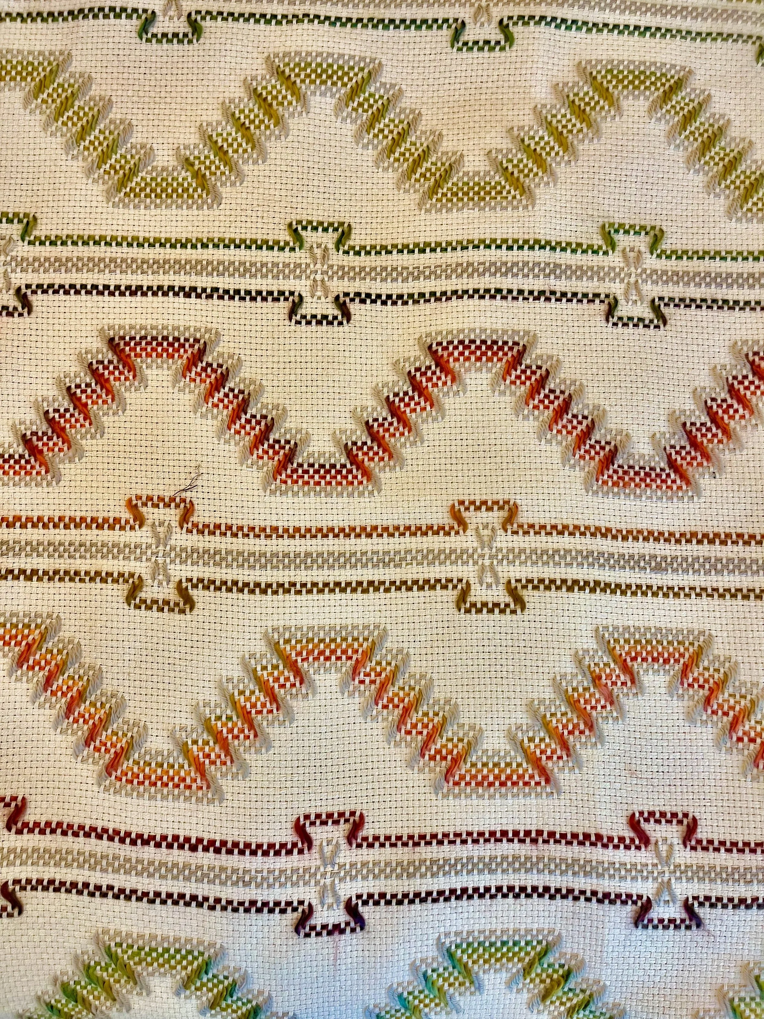 Close-up of a woven textile with colorful zigzag patterns in red, orange, green, and beige.