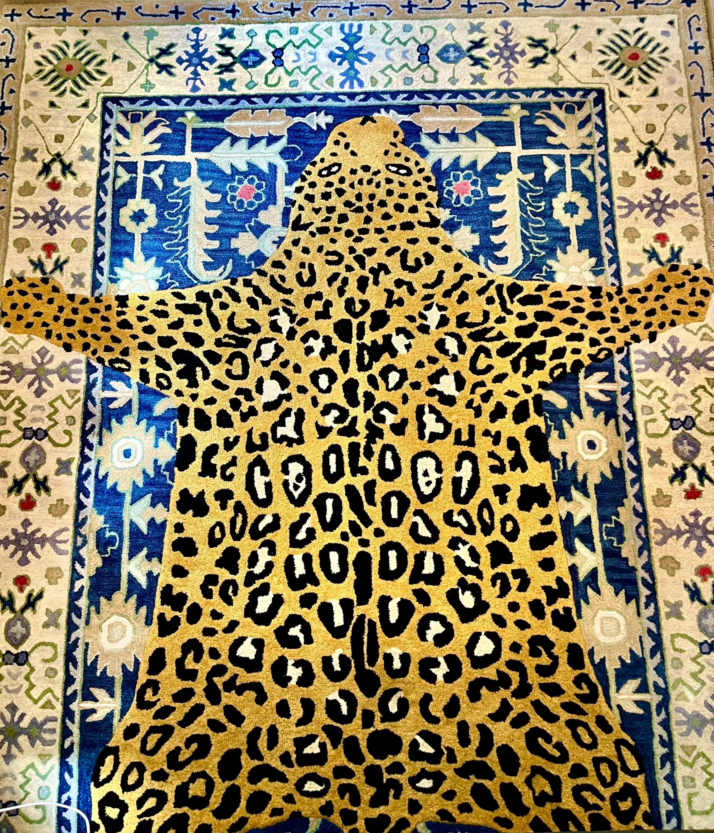 A detailed, colorful patterned rug featuring a large leopard's head centered among various floral and geometric motifs, with a background of intricate borders in shades of blue, green, beige, and black.