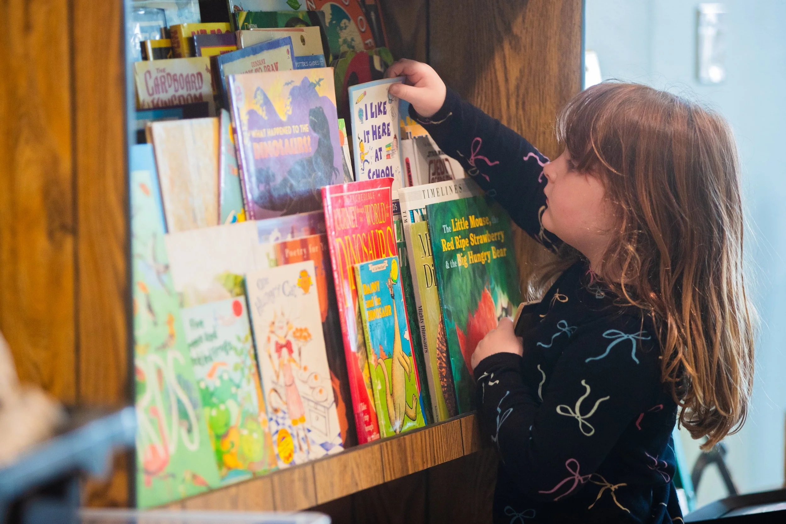 Child selects a book from a shelf at a small private school