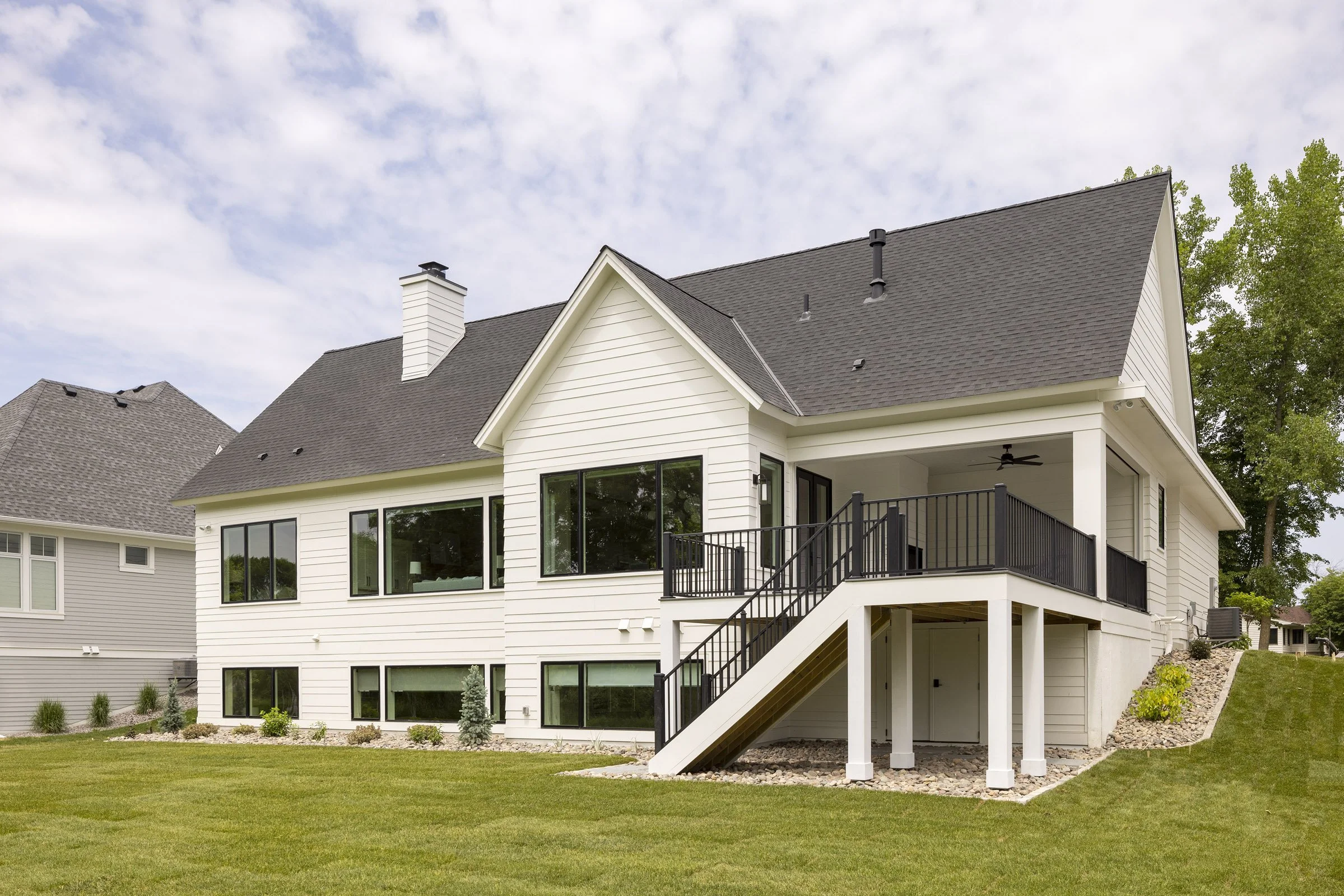 Rear elevation of a Medina residence featuring an elevated covered deck, expansive windows, and outdoor living spaces.