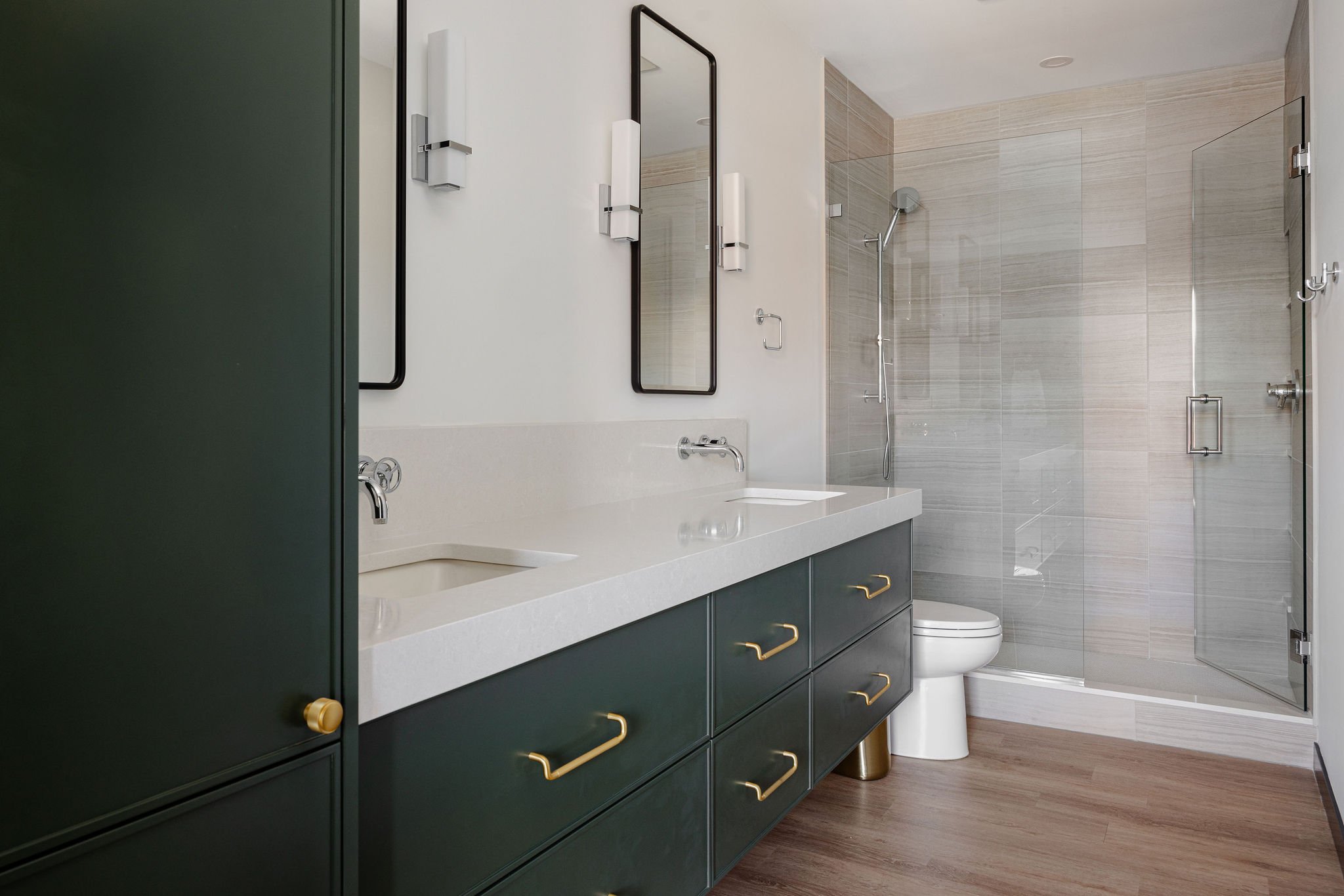 Modern bathroom with custom green vanity, quartz countertops, and glass shower in a luxury auto condo in Medina, Minnesota.