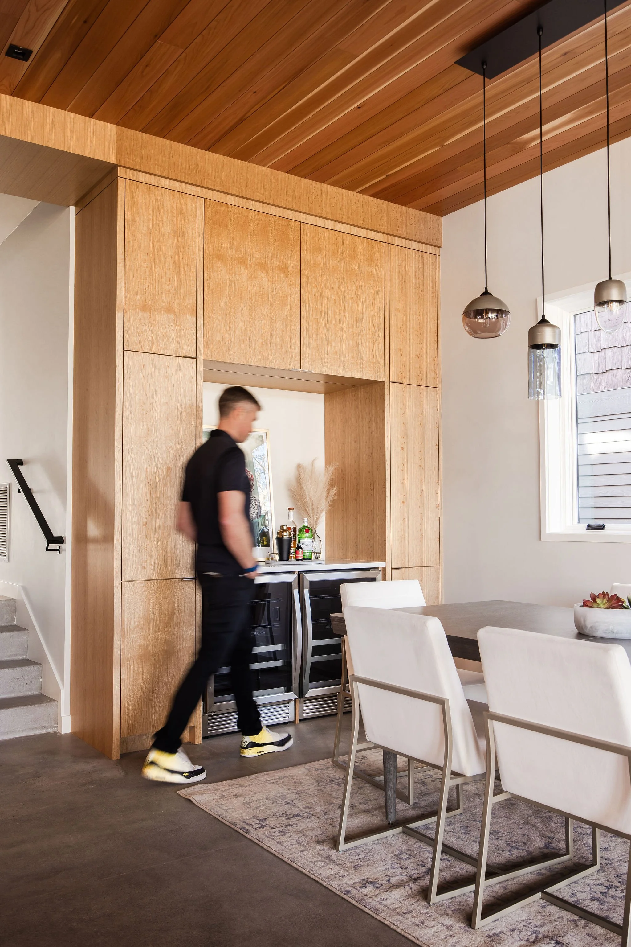 Dining area with built-in bar cabinetry, custom millwork, and contemporary pendant lighting.