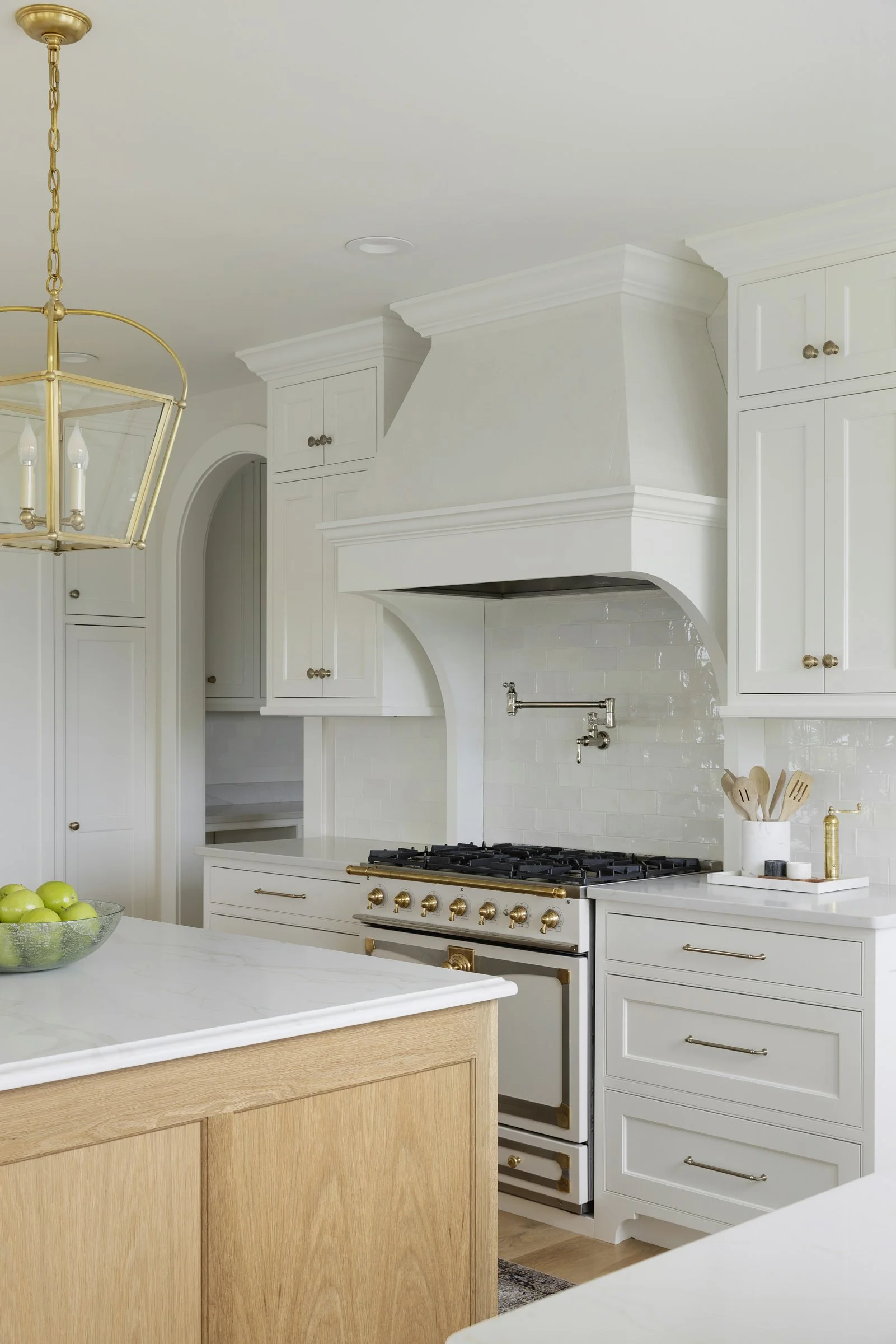 Custom plaster range hood with arched detailing and handcrafted finishes in a Rochester, Minnesota kitchen.
