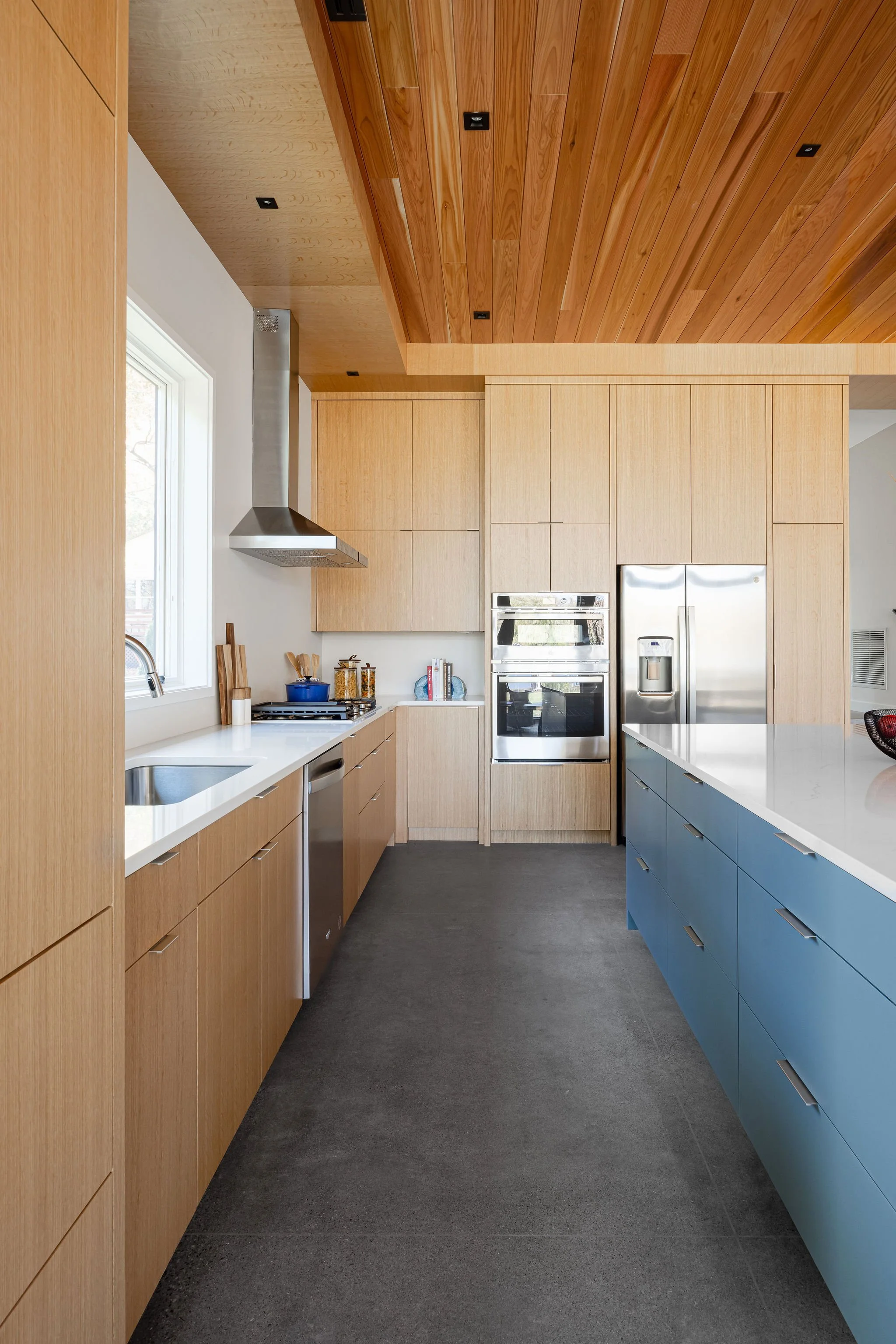 Bright galley kitchen featuring custom millwork, quartz countertops, and natural wood finishes.