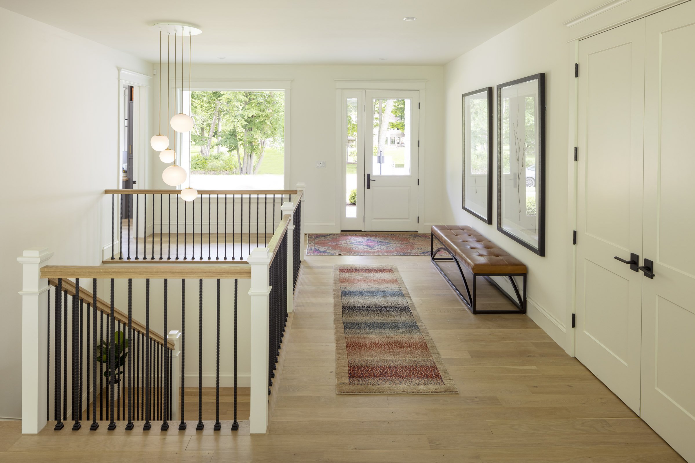 Light-filled foyer in a Medina custom home with globe pendant lighting, white millwork, and natural oak flooring.
