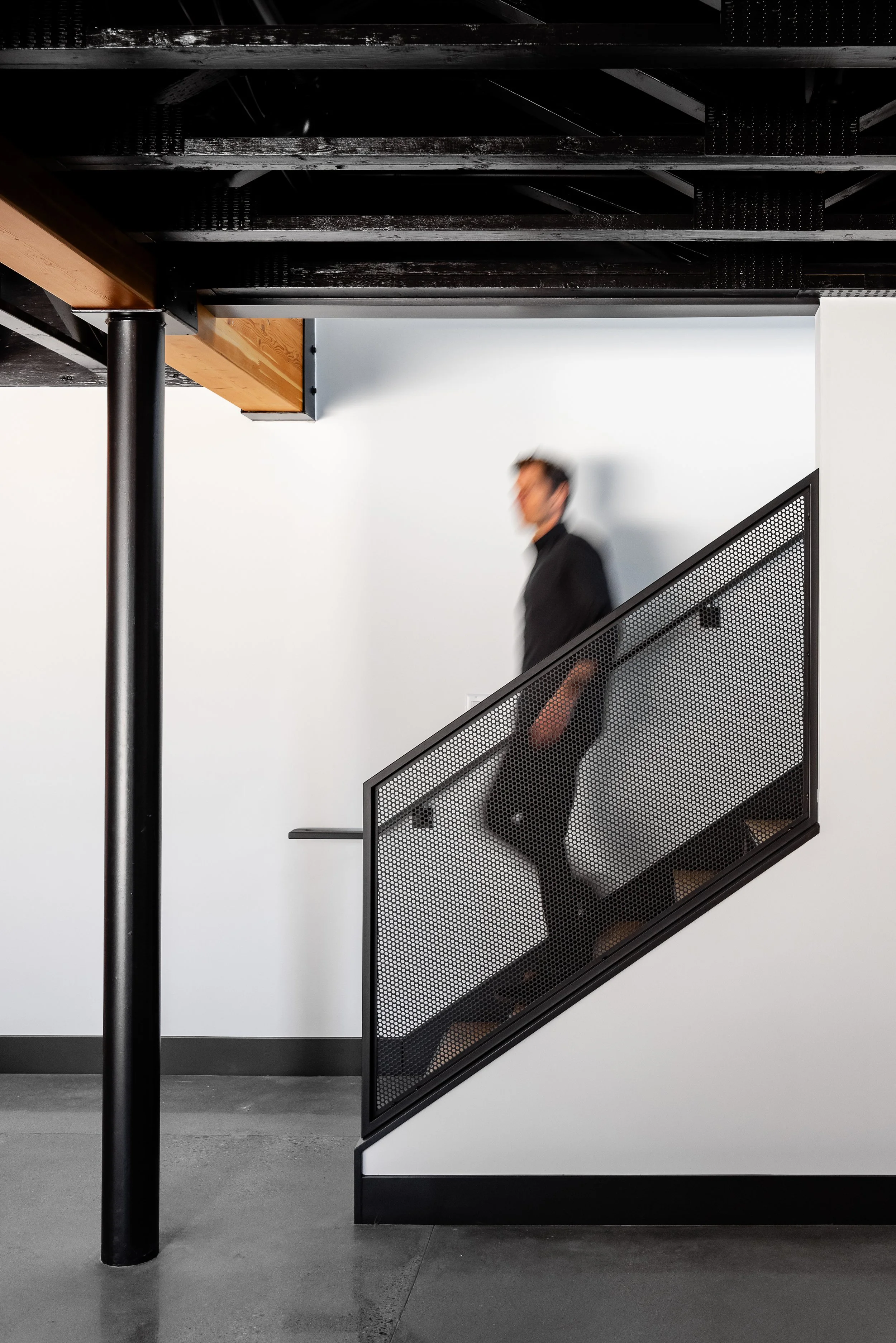 Custom steel staircase with perforated metal railing and exposed structural elements in a Medina luxury auto condo.