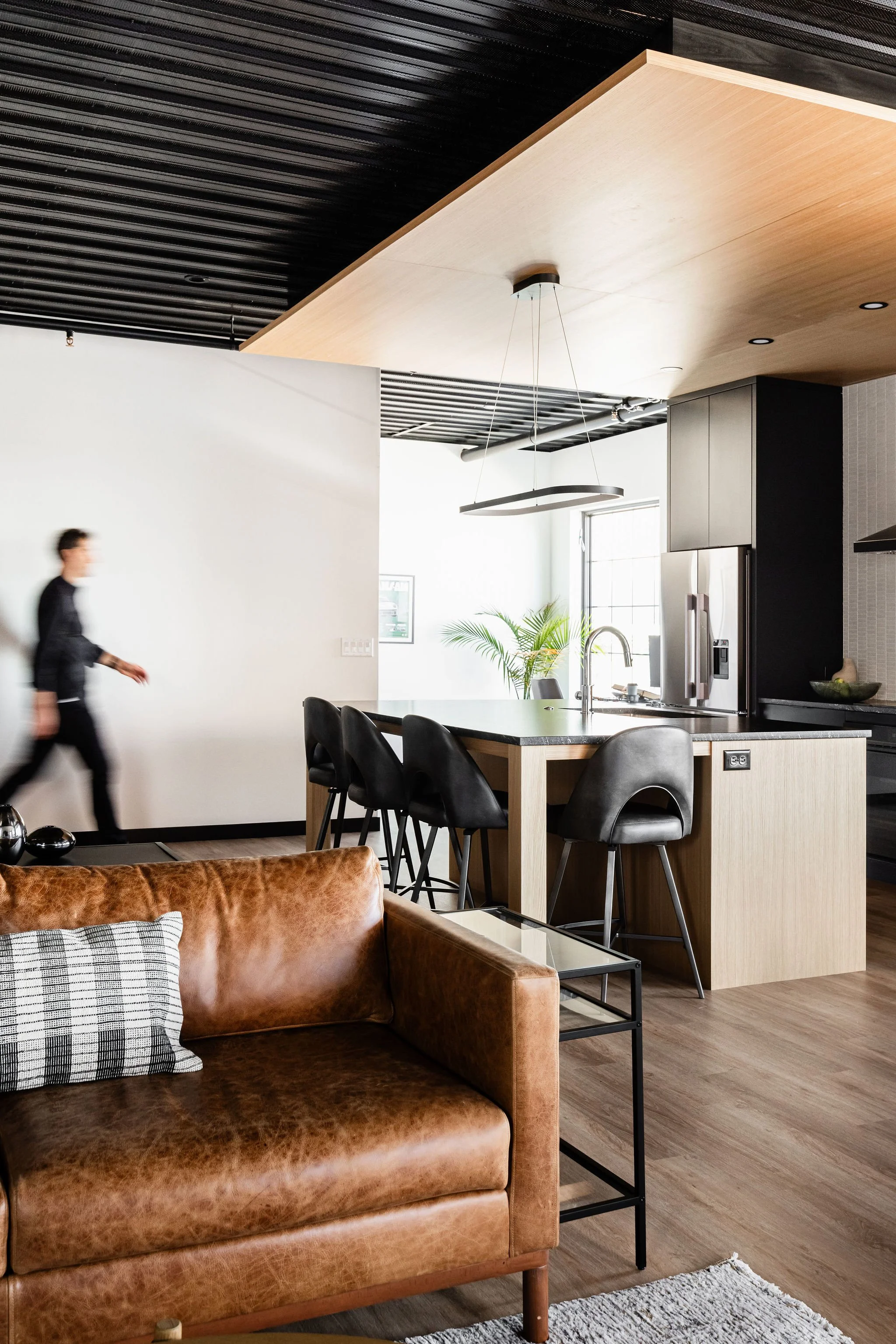 Modern kitchen island with black cabinetry, wood accents, and contemporary lighting in a Medina auto condo.