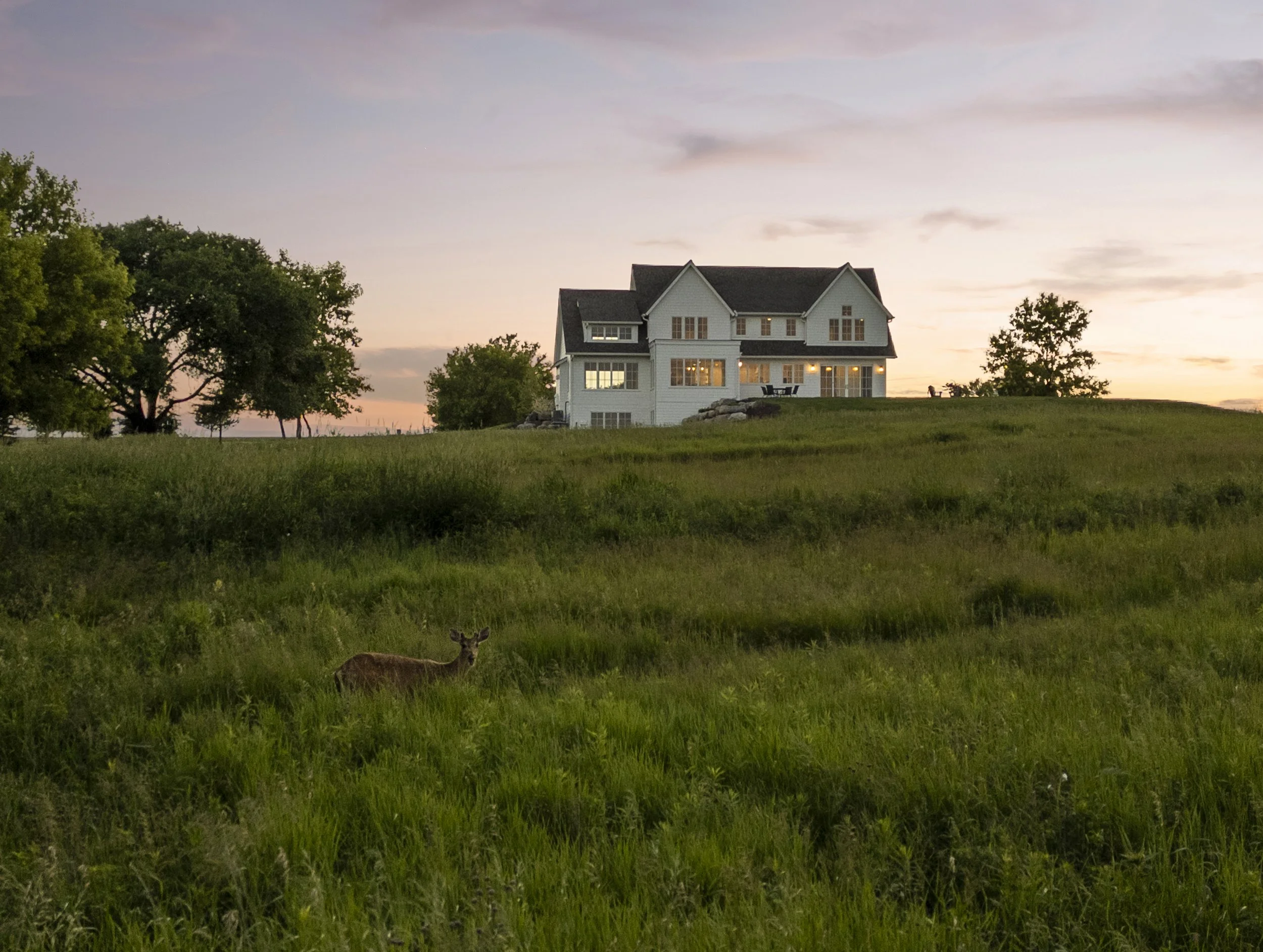 Rochester, Minnesota custom home at sunset overlooking rolling prairie landscape and native grasses.