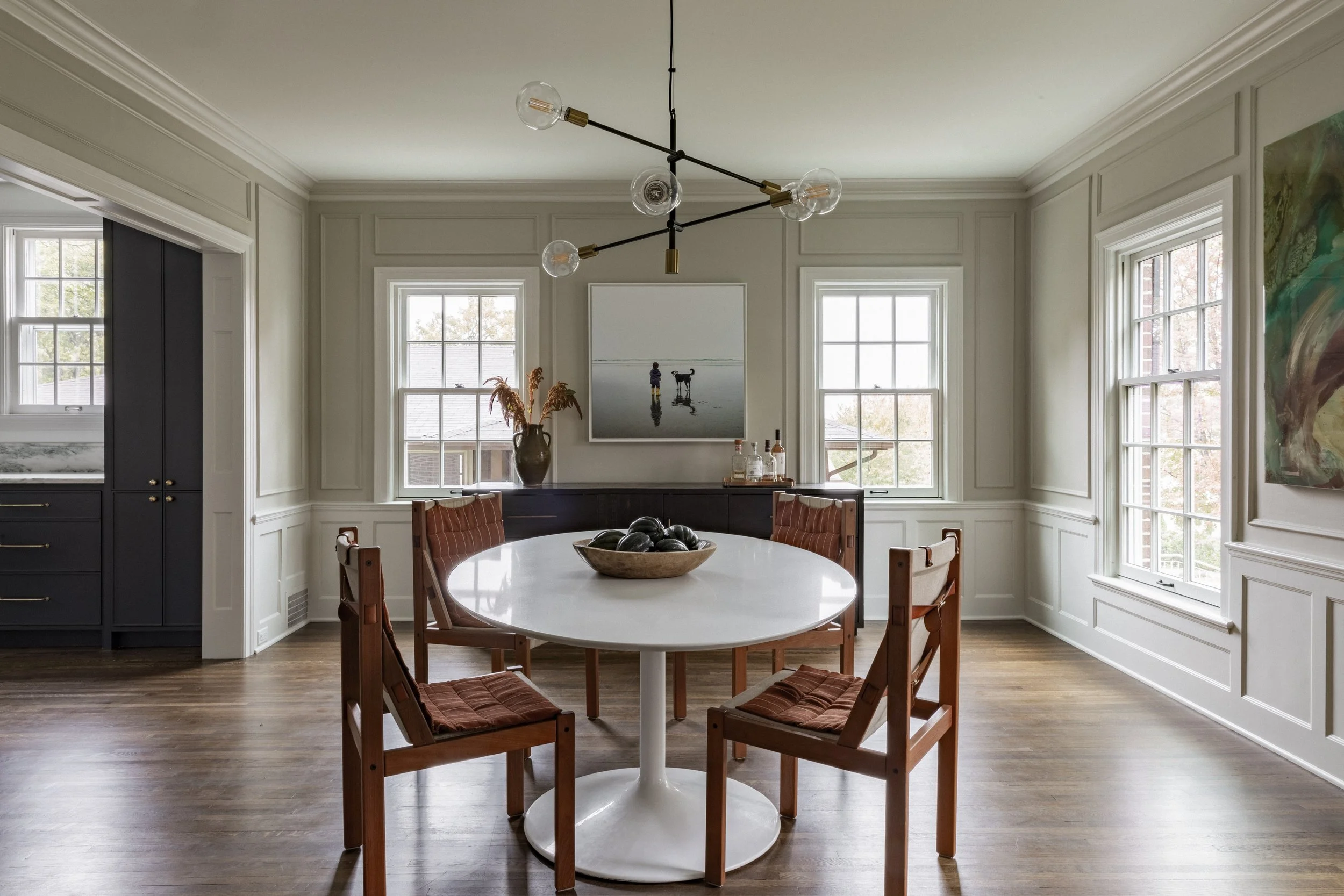 Dining room in a Minneapolis remodel featuring custom wall millwork, large windows, and contemporary furnishings.