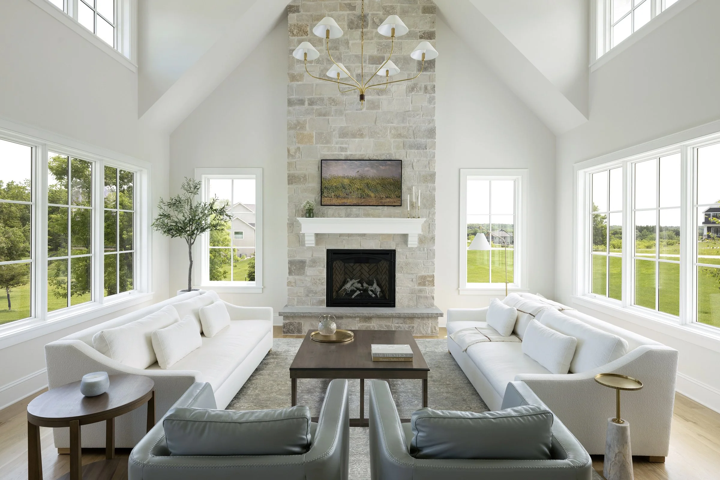 Vaulted great room with oversized windows, custom furnishings, and a limestone fireplace in a Rochester, Minnesota residence.