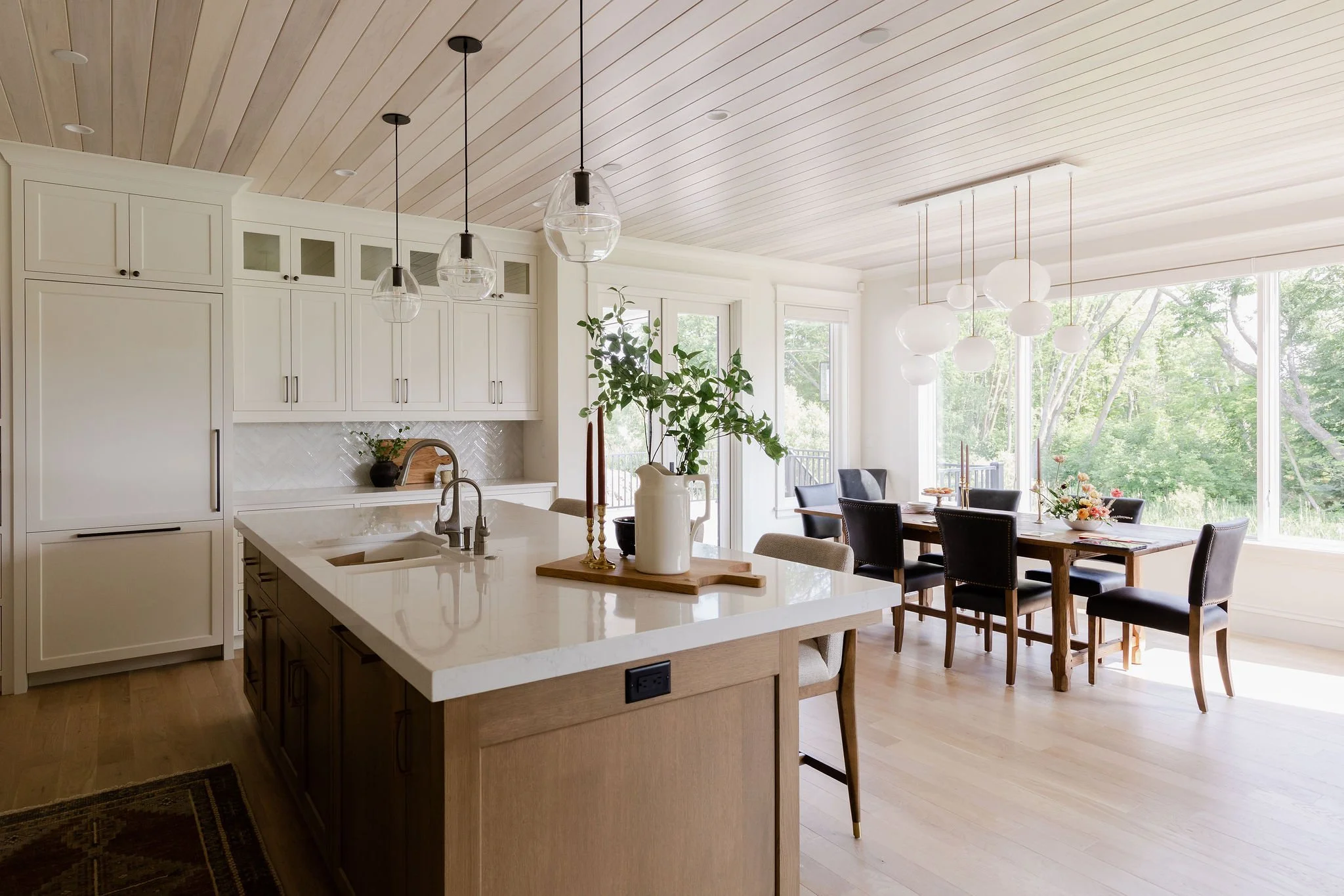 Open kitchen and dining area in a Medina custom home with statement lighting, custom cabinetry, and wooded views.
