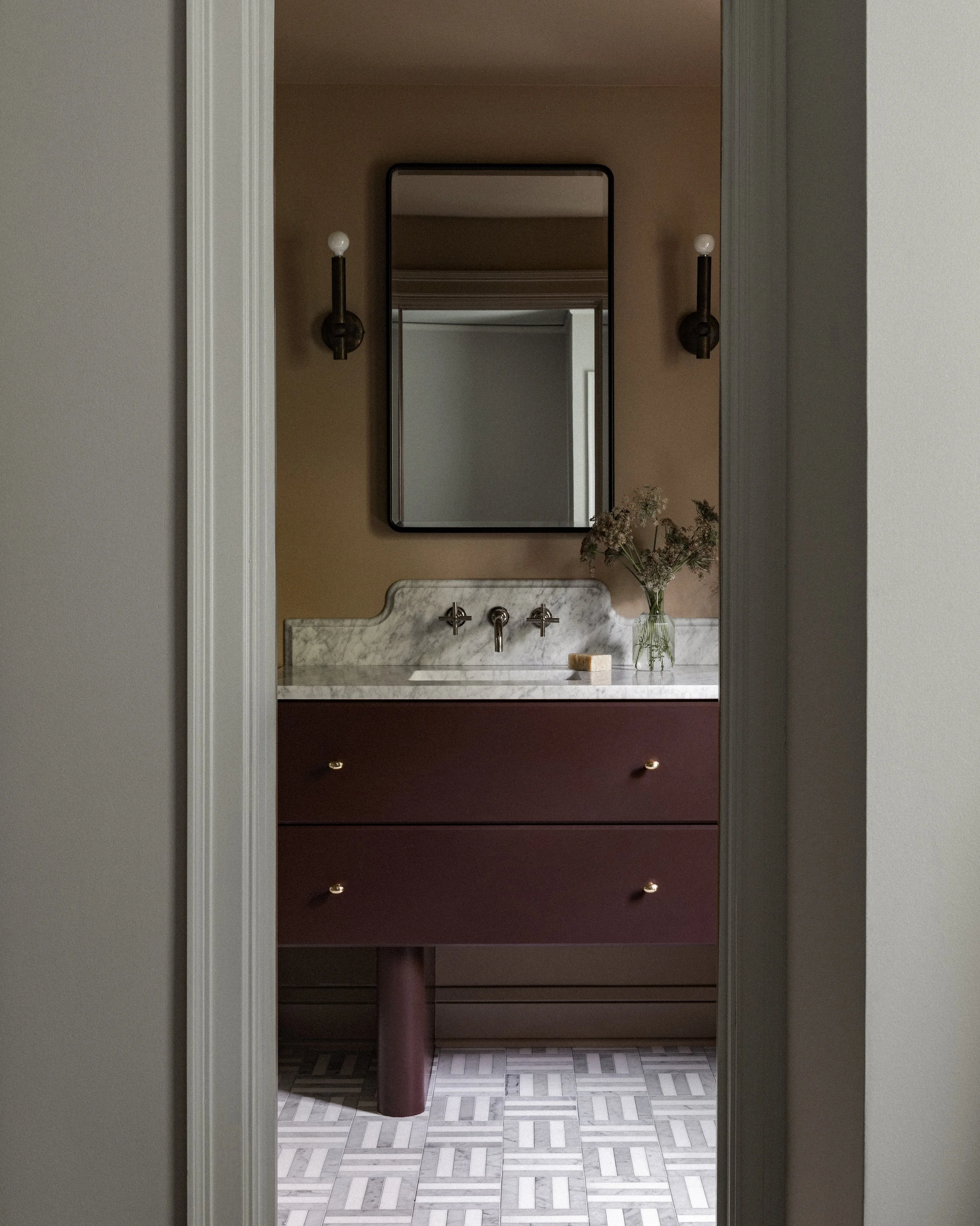 Primary bath in a Minneapolis remodel with a custom vanity, marble countertop, brass fixtures, and decorative wall sconces.
