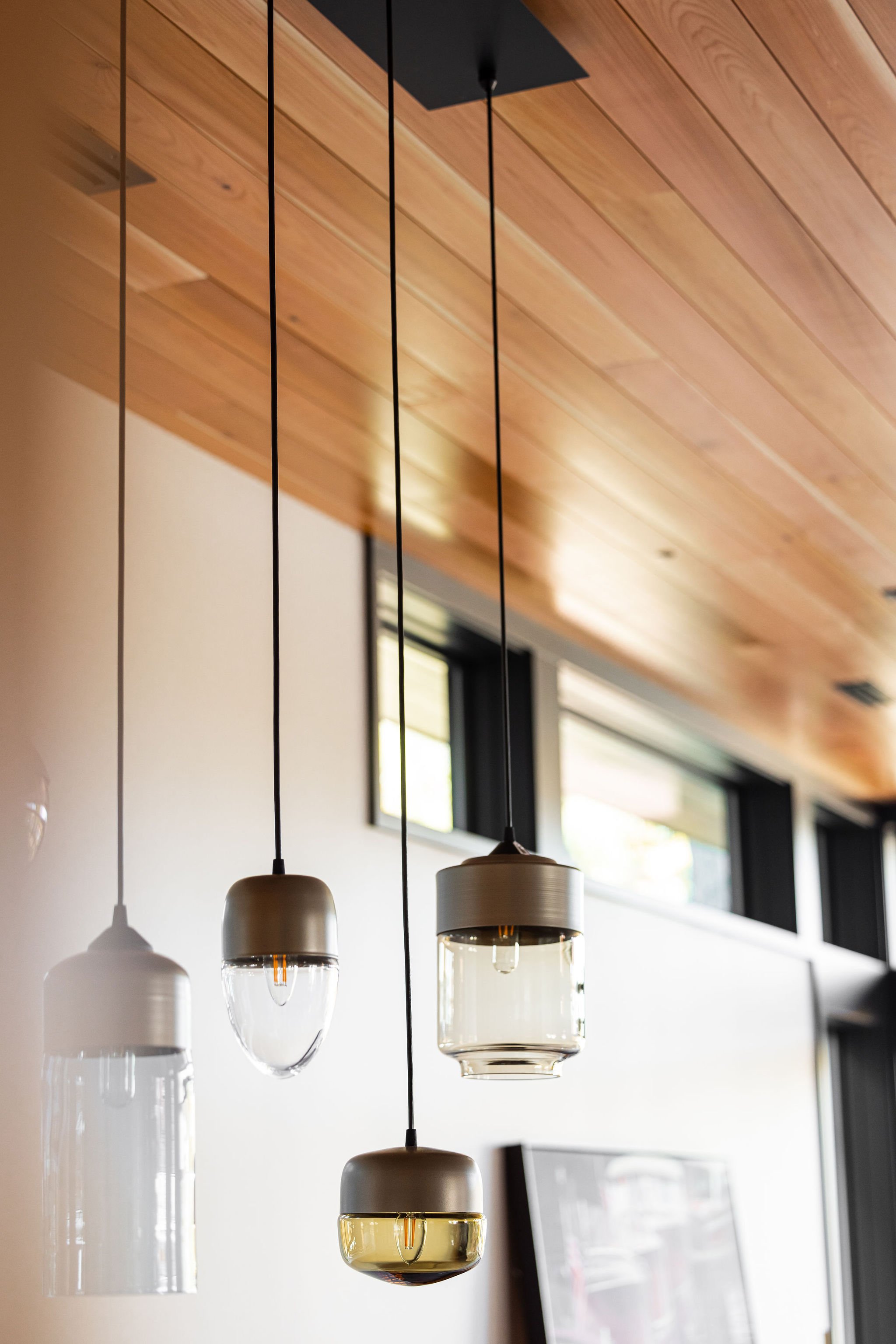 Contemporary designer, hand blown glass, pendant lights suspended beneath a warm cedar ceiling.