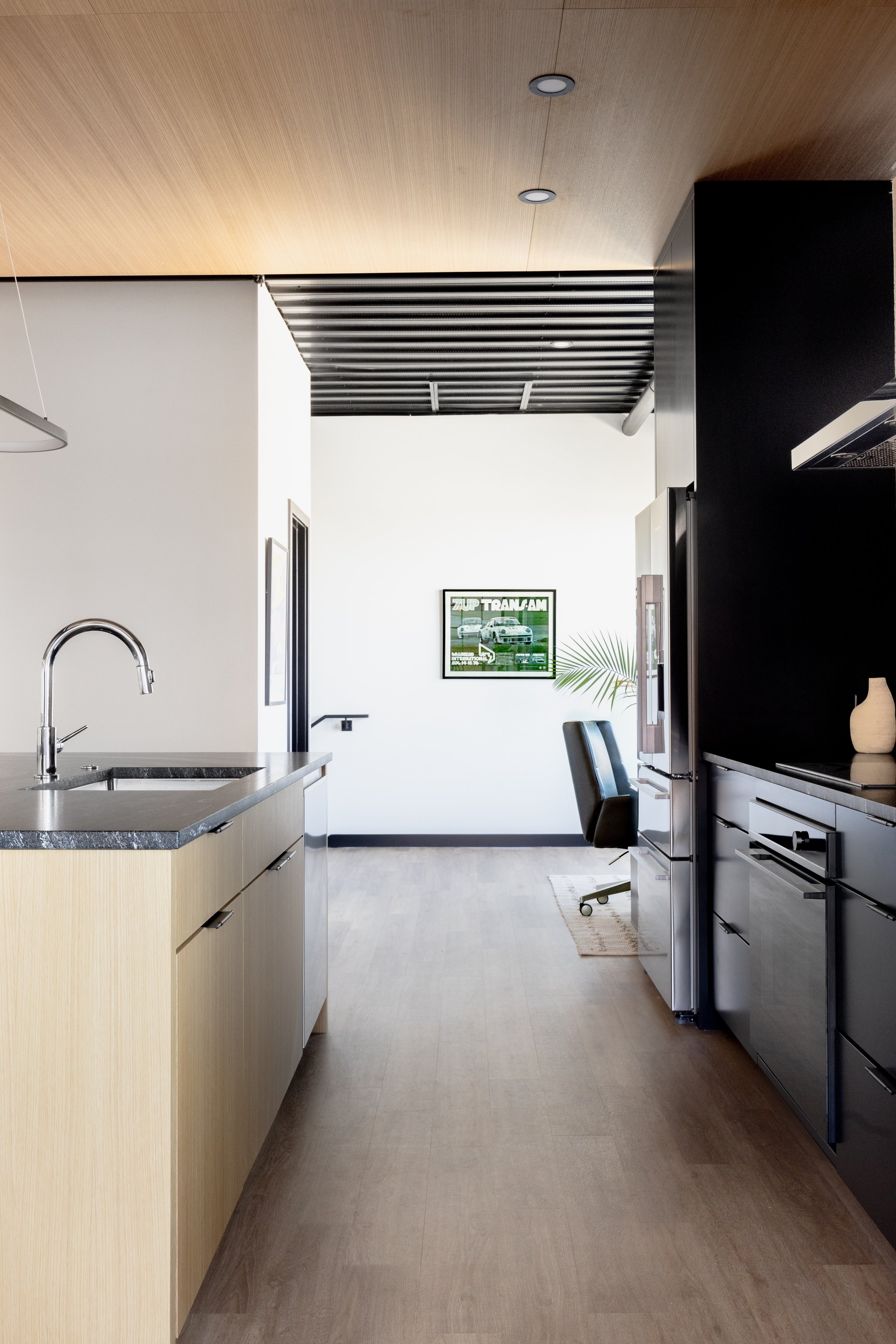 Modern kitchen with wood cabinetry, black accents, and open industrial design in a luxury auto condo in Medina, Minnesota.