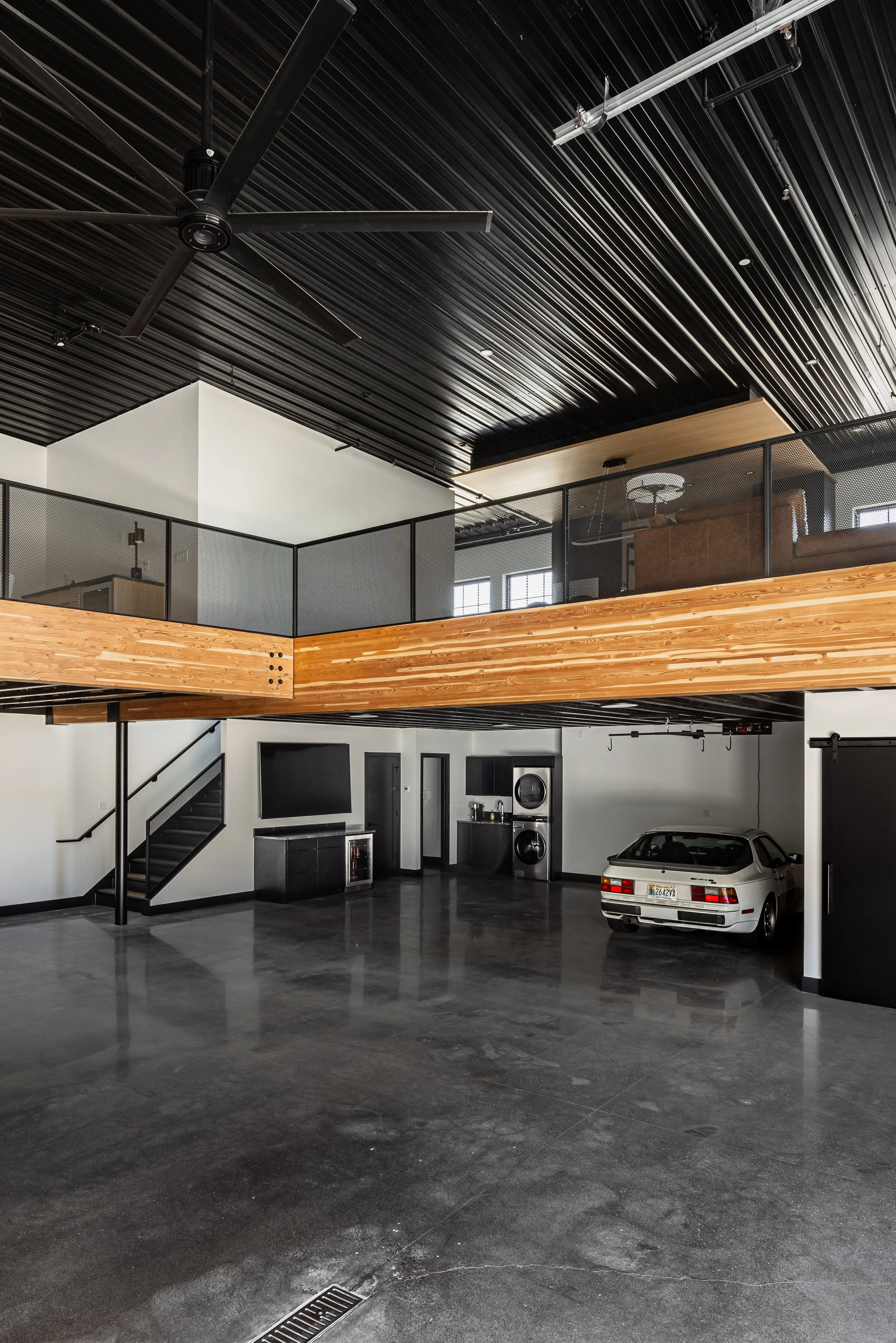 Luxury auto condo garage with mezzanine level, polished concrete floors, and industrial steel detailing in Medina, Minnesota.