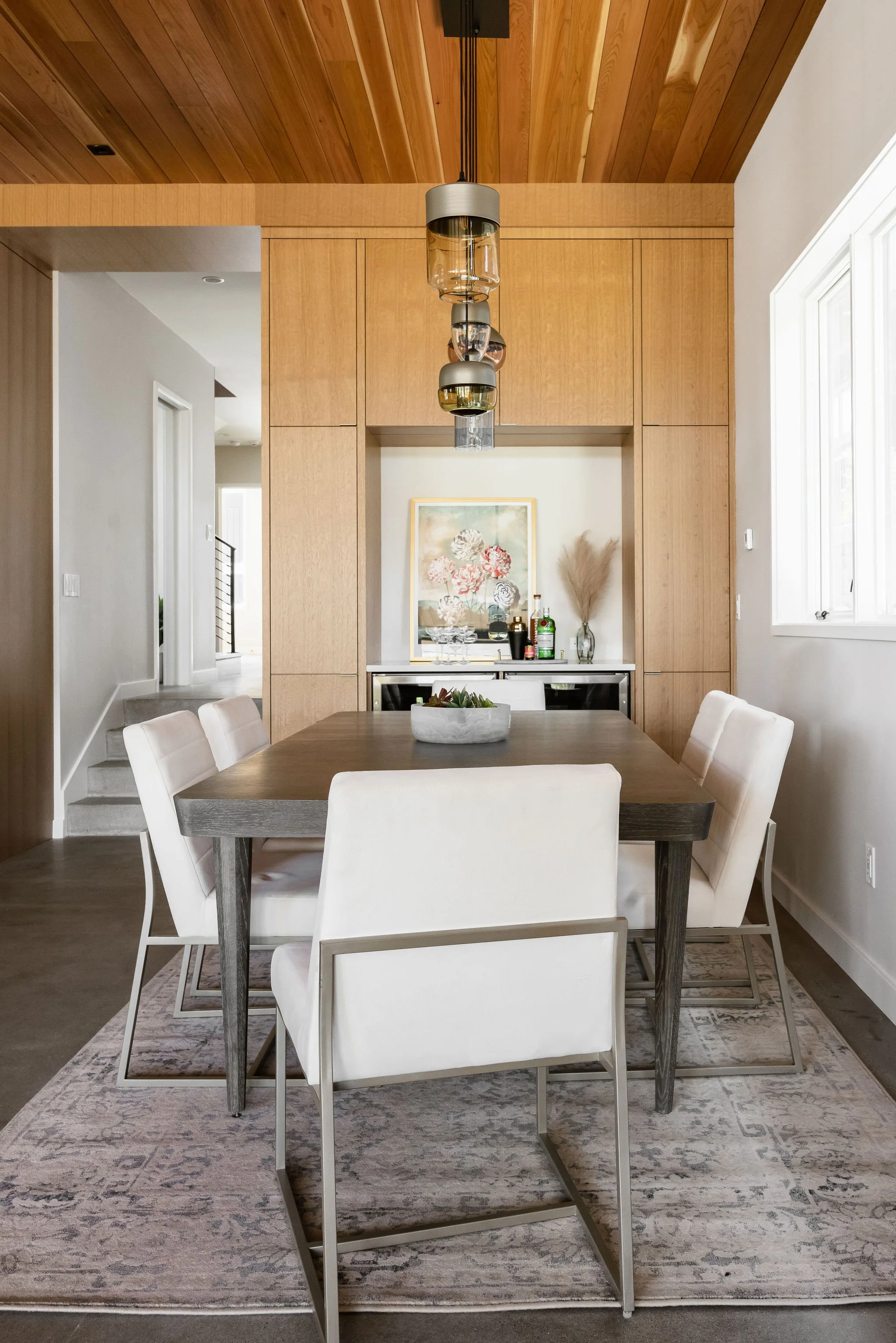 Dining area with built-in bar cabinetry, custom millwork, and contemporary pendant lighting.