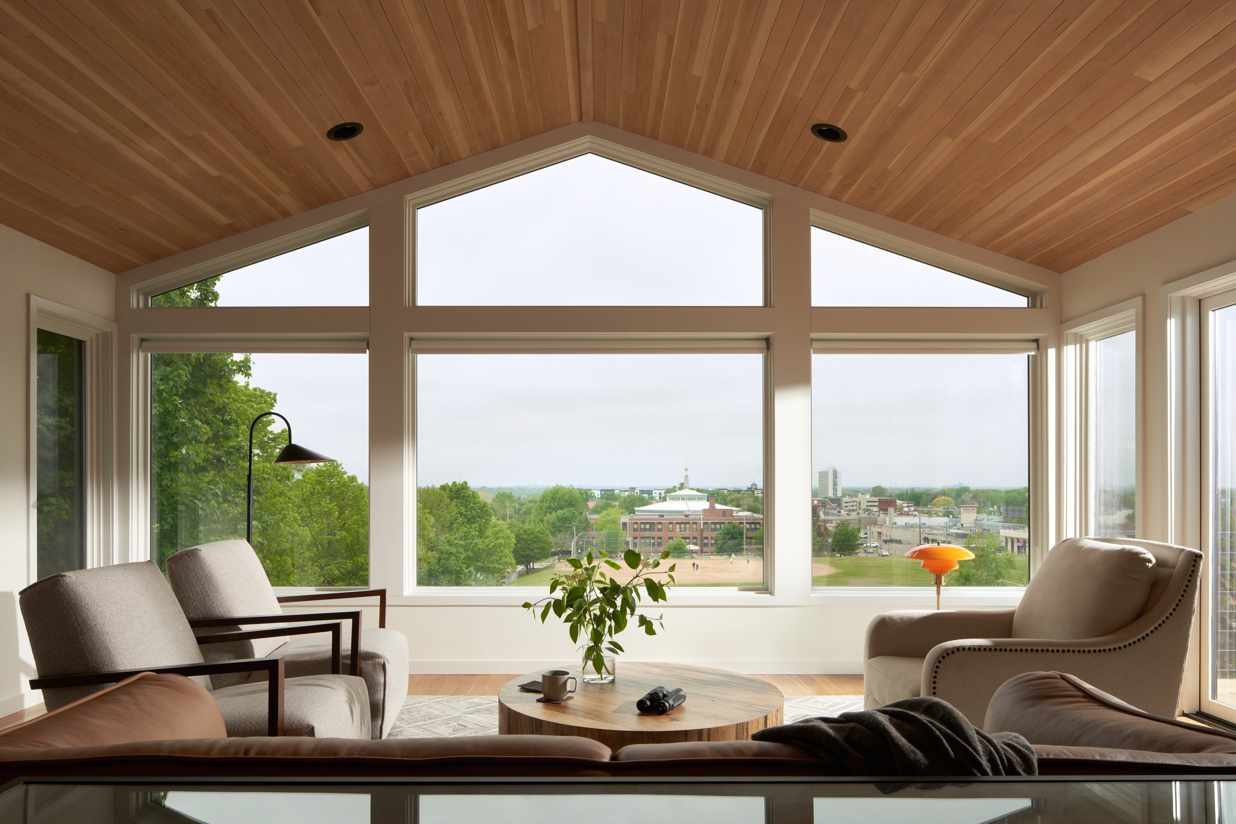 Great room with vaulted cedar ceiling, expansive windows, and panoramic views at Parkway Heritage, a St. Paul home renovation by Karl Adalbert Architecture + Design.