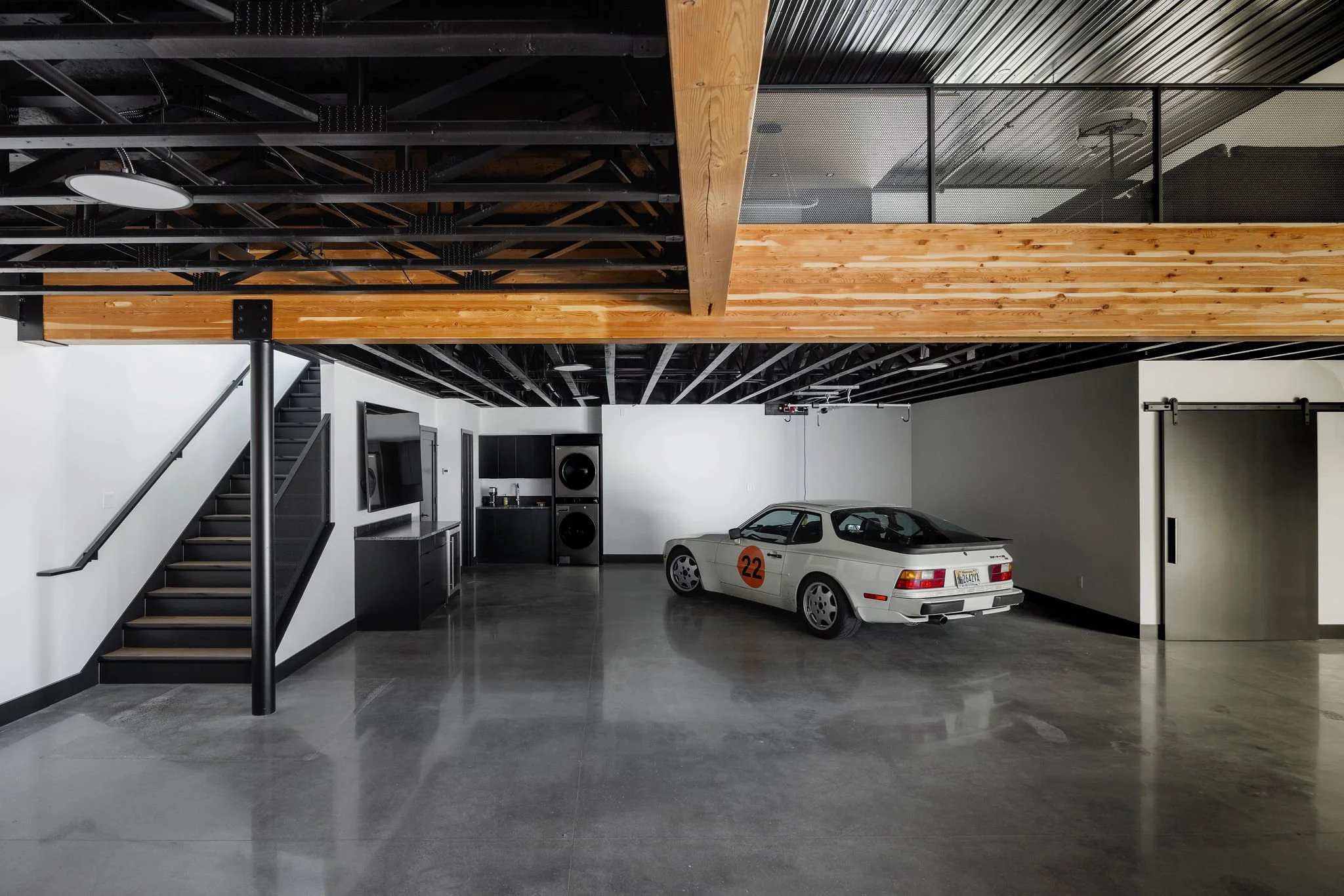 Luxury garage with polished concrete floors, exposed steel beams, and contemporary design.