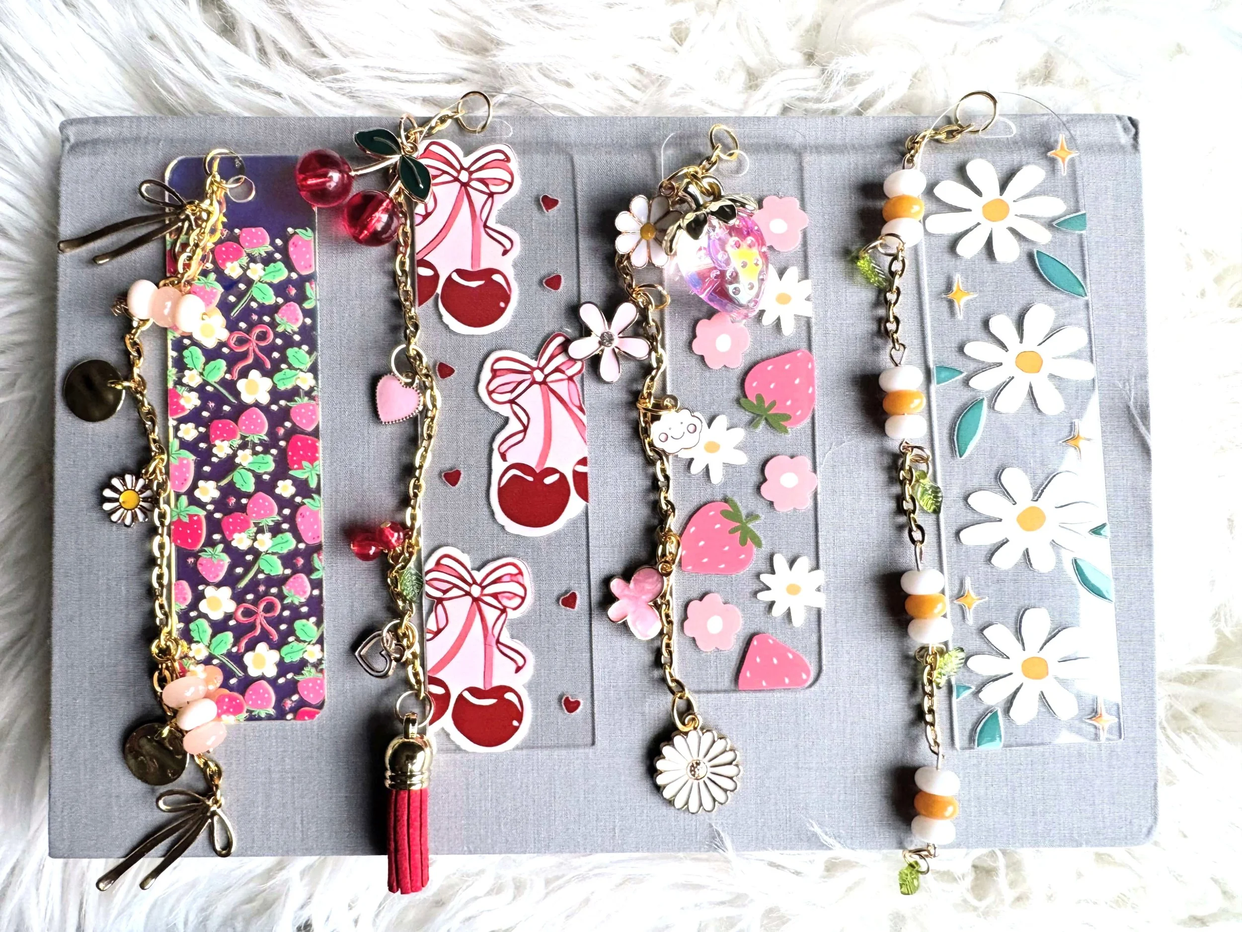 Display of various colorful acrylic bookmarks with permanent UV DTF designs.  Accompanied with a chain tassel filled with unique charms.