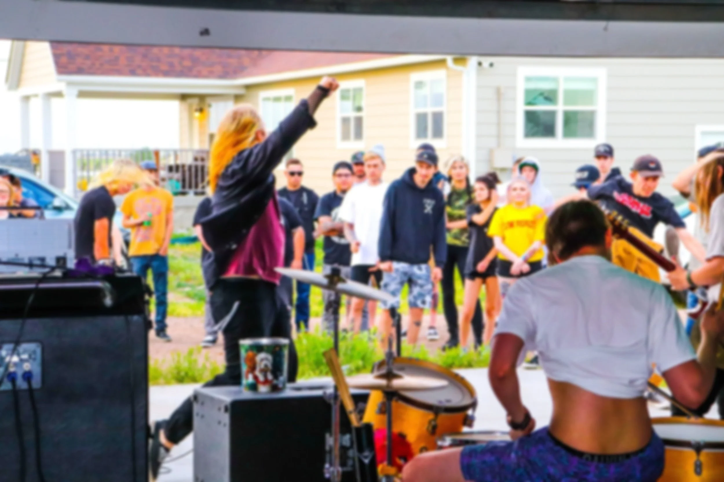 A group of people gathered outside in front of houses, with some standing and one raising their fist, possibly during a social or community event.