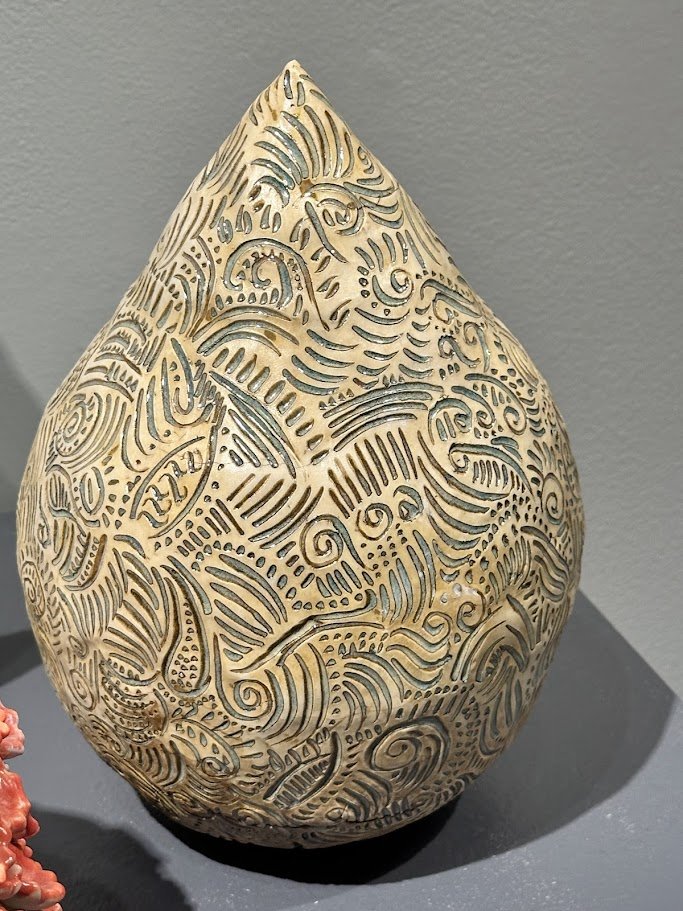 Decorative carved gourd or teardrop-shaped object with intricate swirling patterns and cutouts.