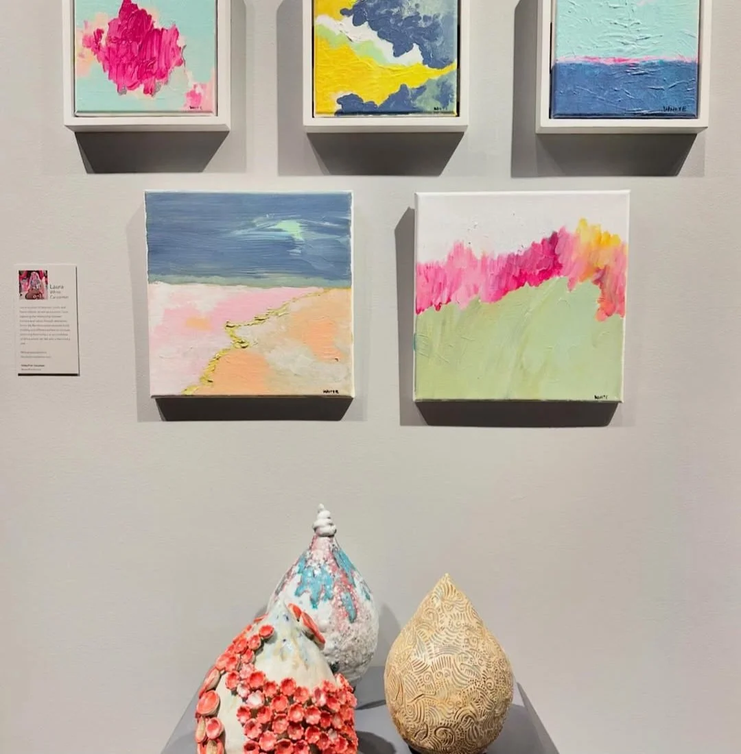 Image of an art display with five small paintings of abstract landscapes on the wall, featuring pastel colors of sky, clouds, and fields. Below the paintings, there are three decorative vases with textured surfaces and colorful accents.