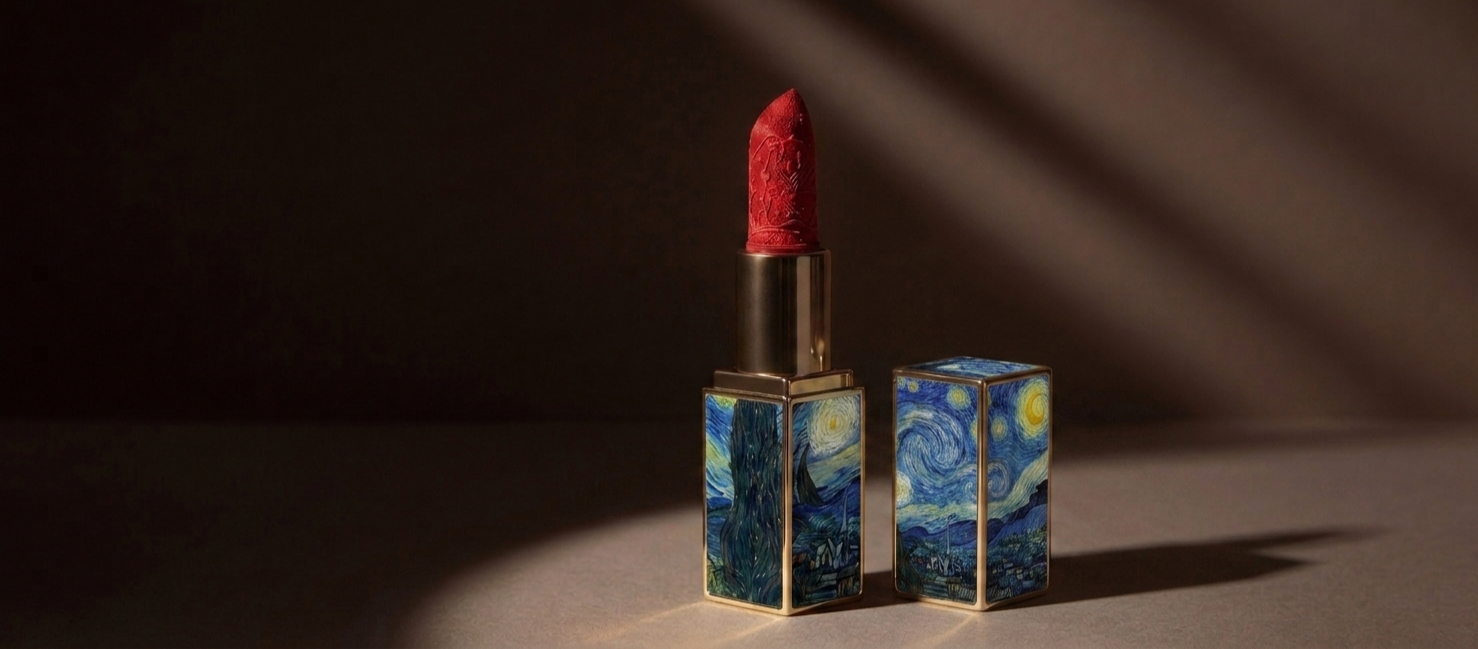 A  natural lipstick with a constellation pattern inside a Van Gogh Starry Night design on the case, paired with its matching cap, placed on a flat surface with a shadowed background.
