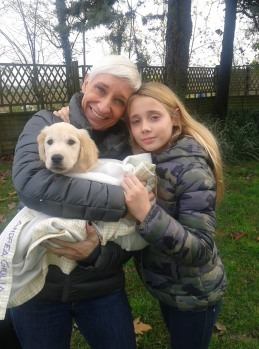 Una donna anziana, una ragazza adolescente e un cane cucciolo giocano all'aperto in giardino.