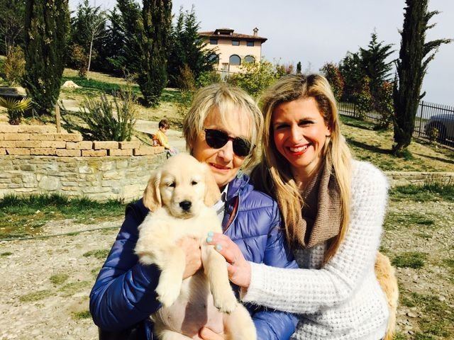 Due donne sorridenti che tengono un cane a cuccia gialla in un parco all'aperto