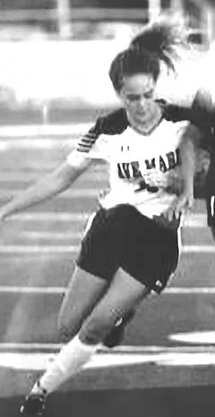 A female athlete in a sports uniform, running and working out on a track or field. College athlete women's soccer.