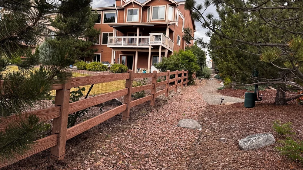 Cedar split rail fence along a gravel path beside a house