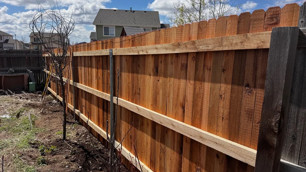 Cedar privacy fence with horizontal rails running along a yard