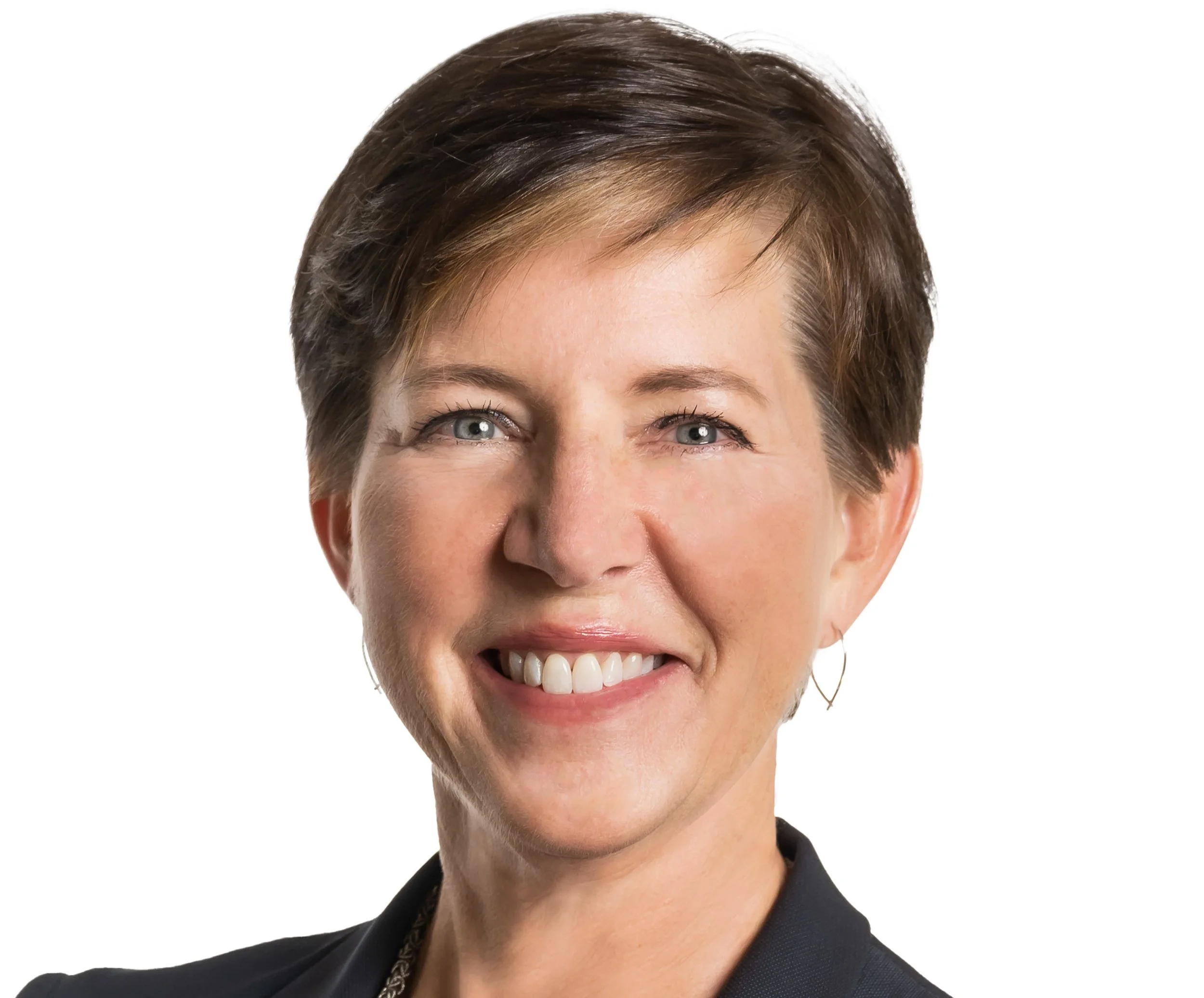 Close-up of a smiling woman with short brown hair, blue eyes, and earrings, wearing a black blazer and necklace, against a white background.