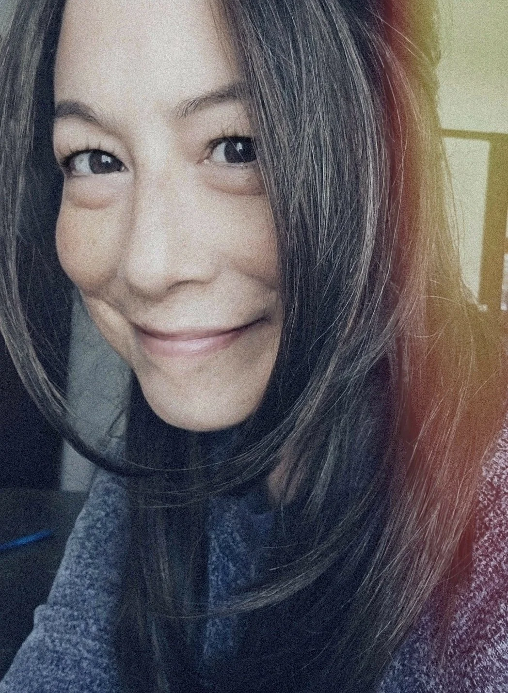 Close-up of Frannie James, a smiling woman with long dark hair, light skin, and dark eyes, indoors with a slightly blurred background.