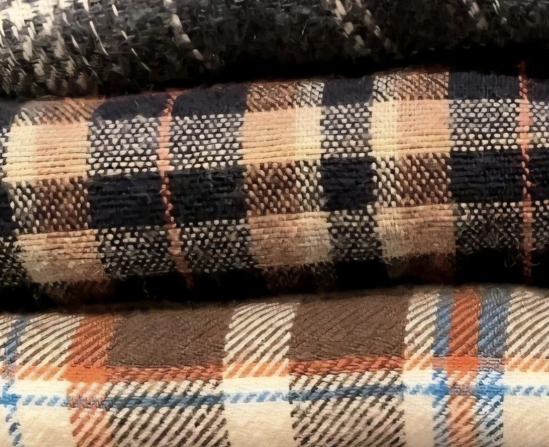 Close-up of overlapping, folded flannel shirts with different color patterns and textures