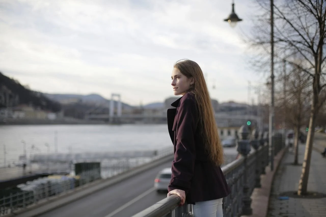woman-in-violet-coat-standing-near-metal-railing