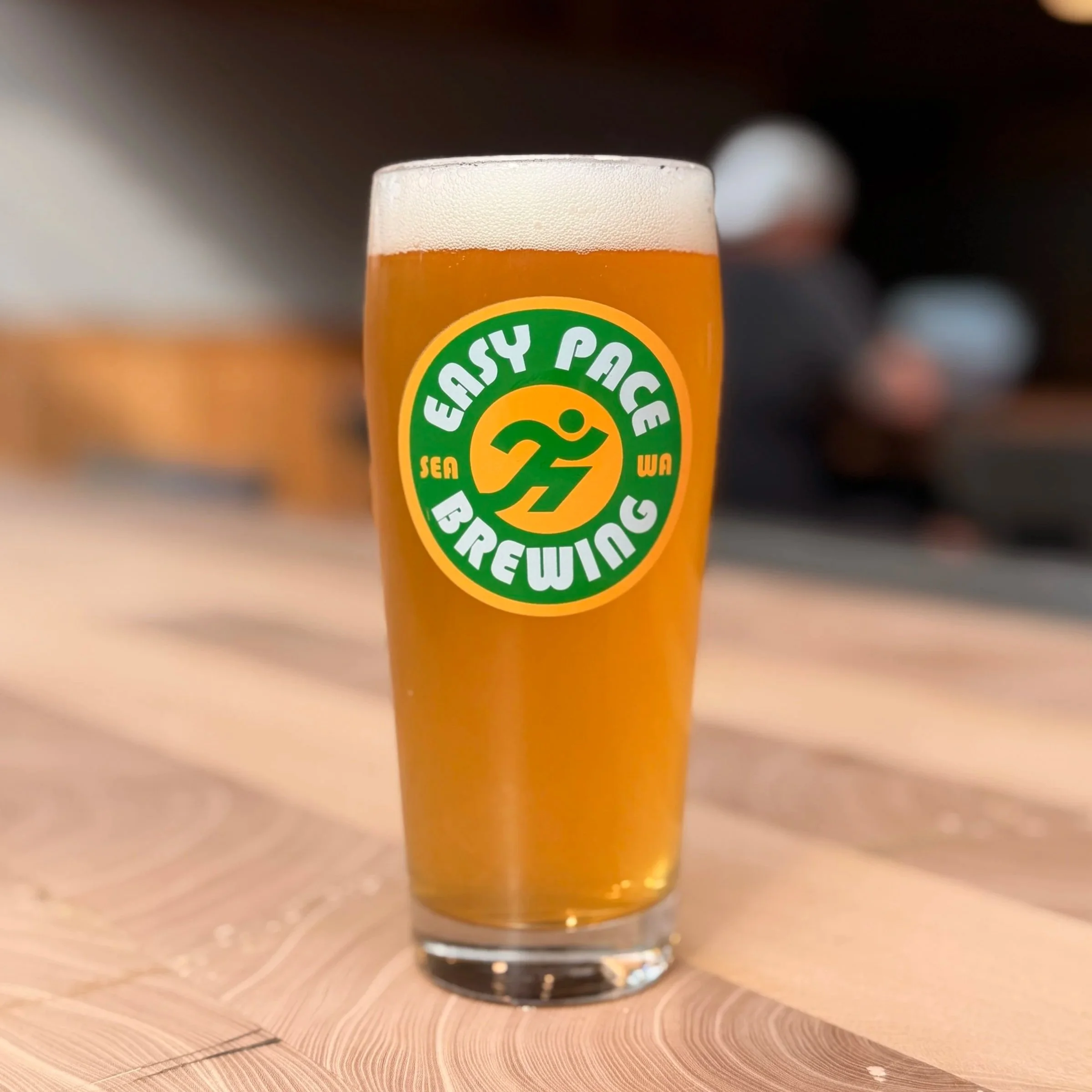 A glass of beer with a frothy head on a wooden table.
