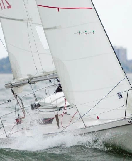 A sailboat racing on the water with its sails catching wind